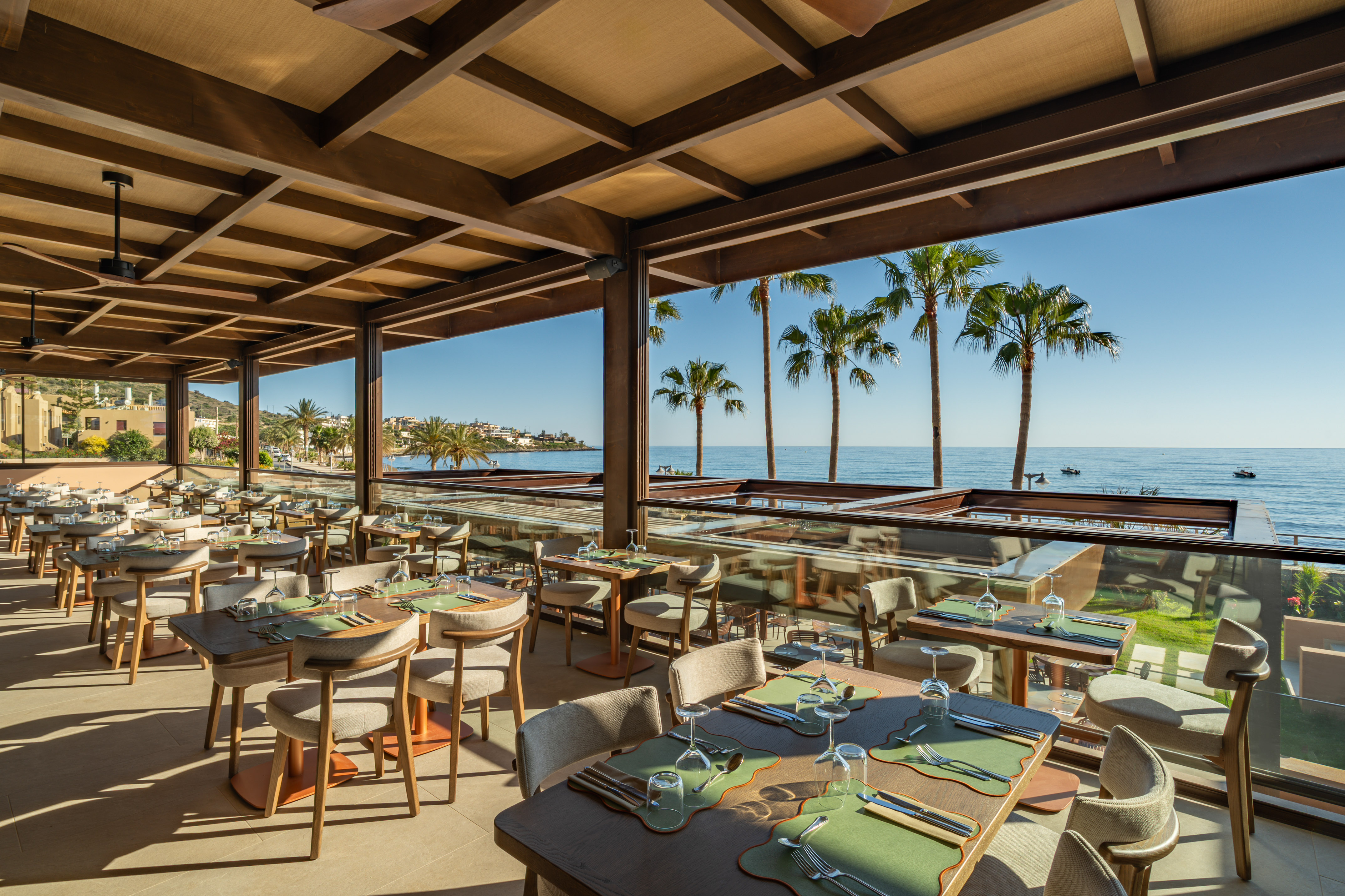 Luxury beachfront restaurant with ocean view and palm trees.