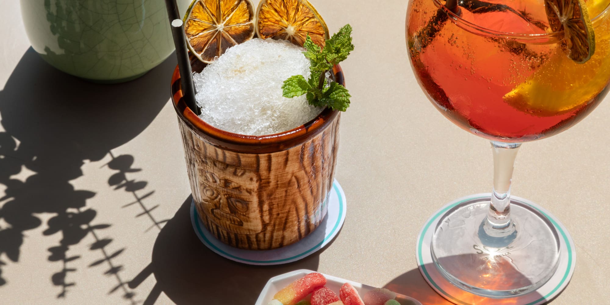 Summer drinks: shaved ice tiki cocktail, orange spritz, with dried citrus & gummies.