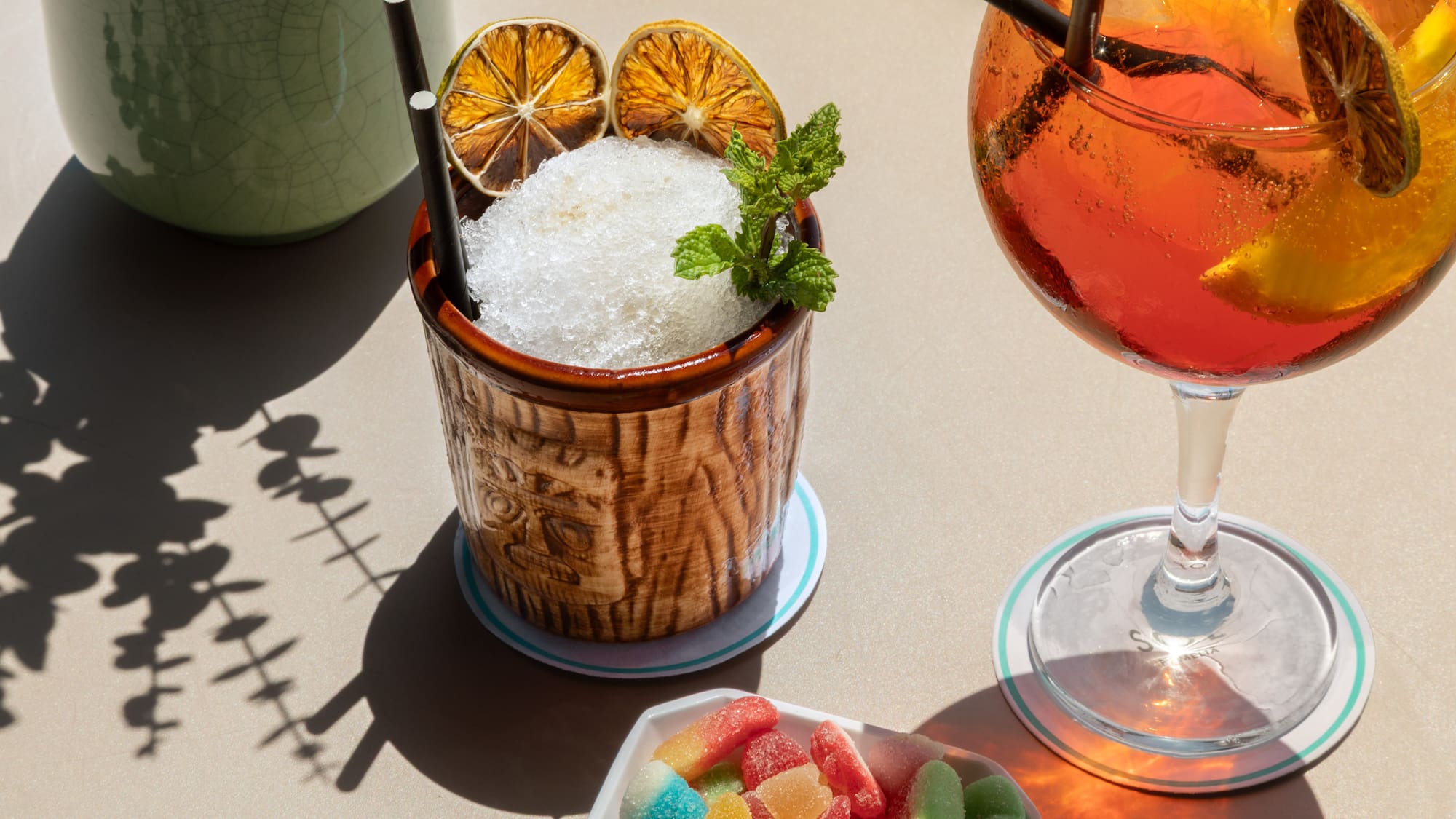 Summer drinks: shaved ice tiki cocktail, orange spritz, with dried citrus & gummies.