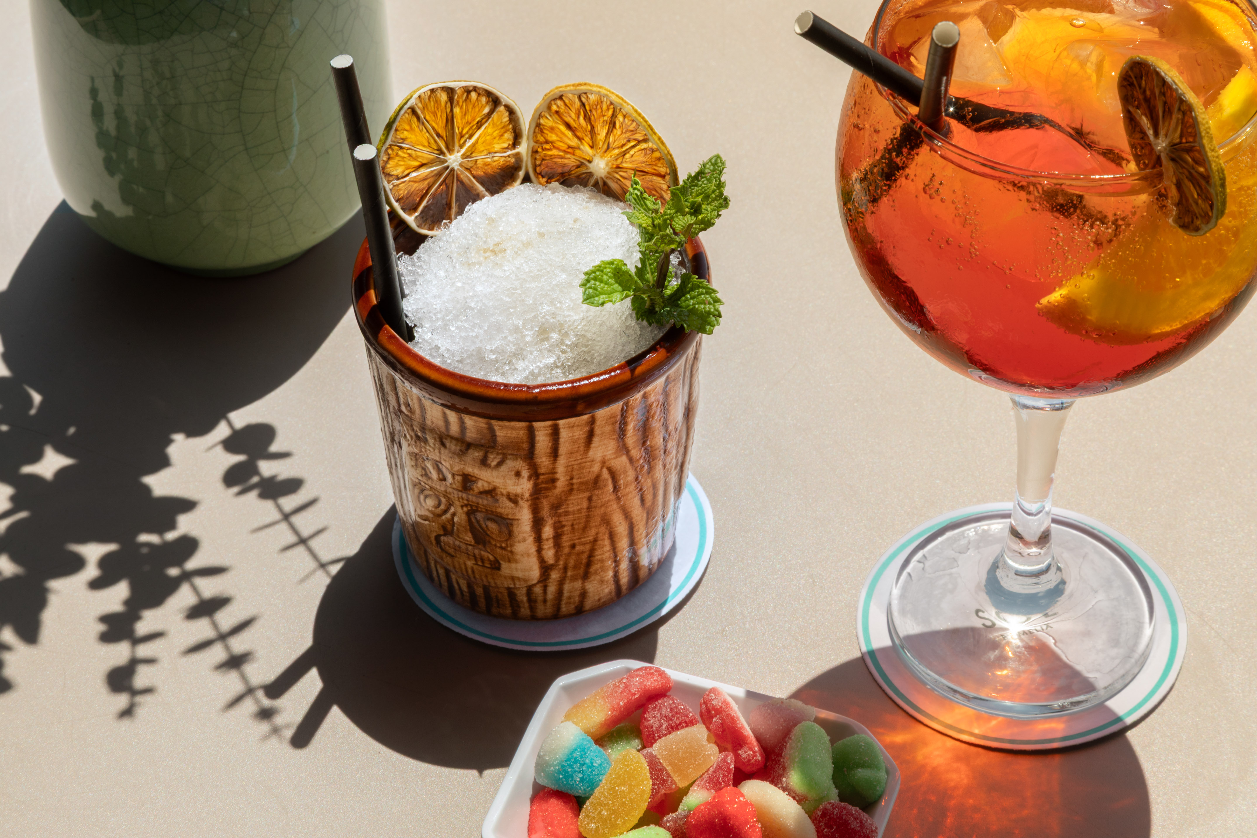 Summer drinks: shaved ice tiki cocktail, orange spritz, with dried citrus & gummies.