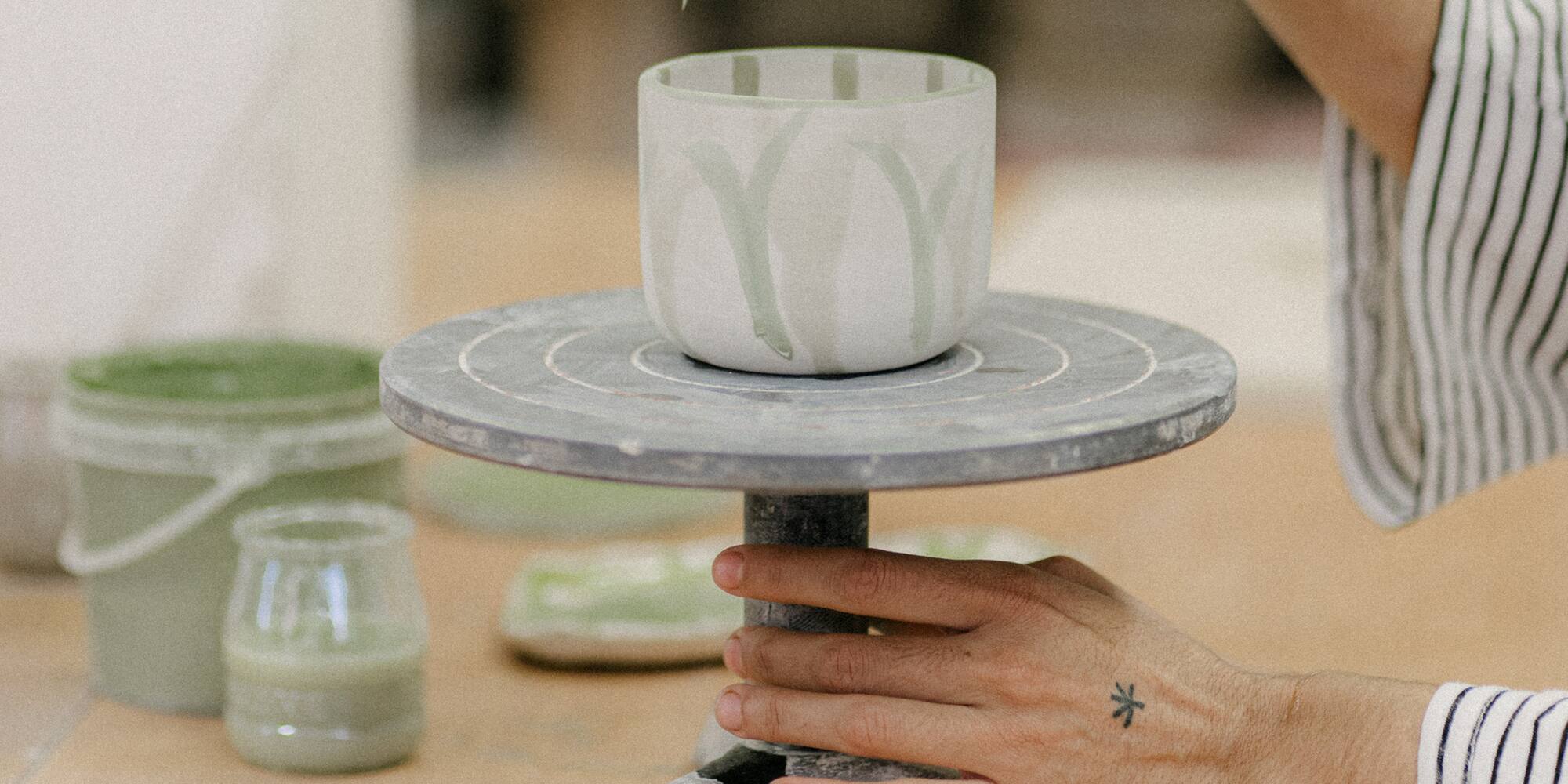 a person painting a cup on a table