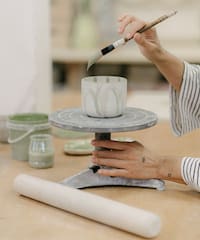 a person painting a cup on a table