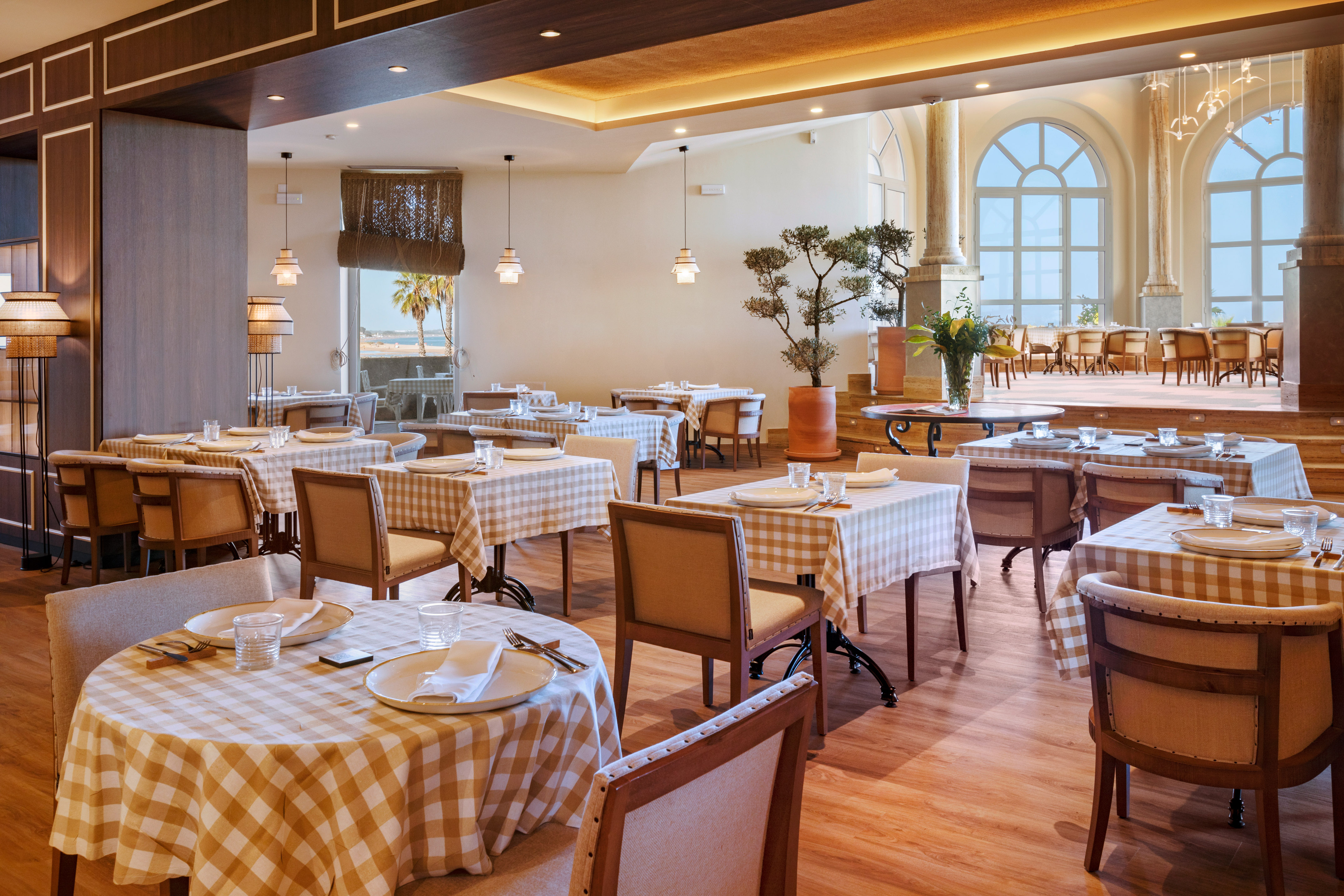 Restaurant dining area with checkered tables, elegant chairs, and an ocean view.