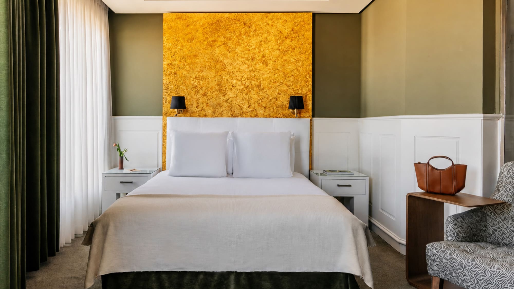 Modern hotel bedroom with gold accent wall, olive green, and white decor.
