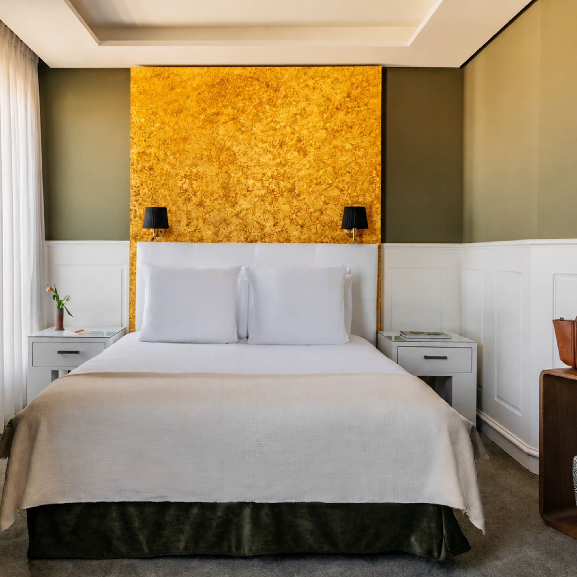 Modern hotel bedroom with gold accent wall, olive green, and white decor.