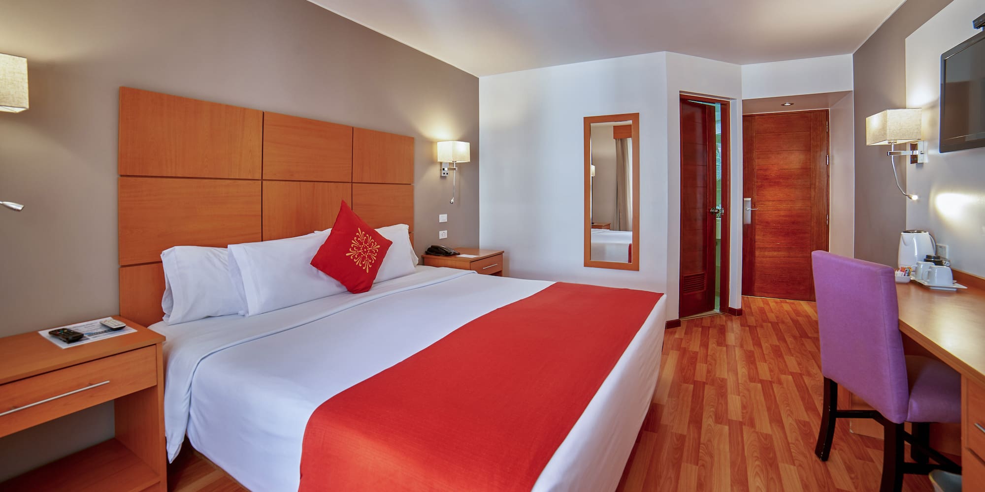 a bed with a red pillow and wood paneled headboard