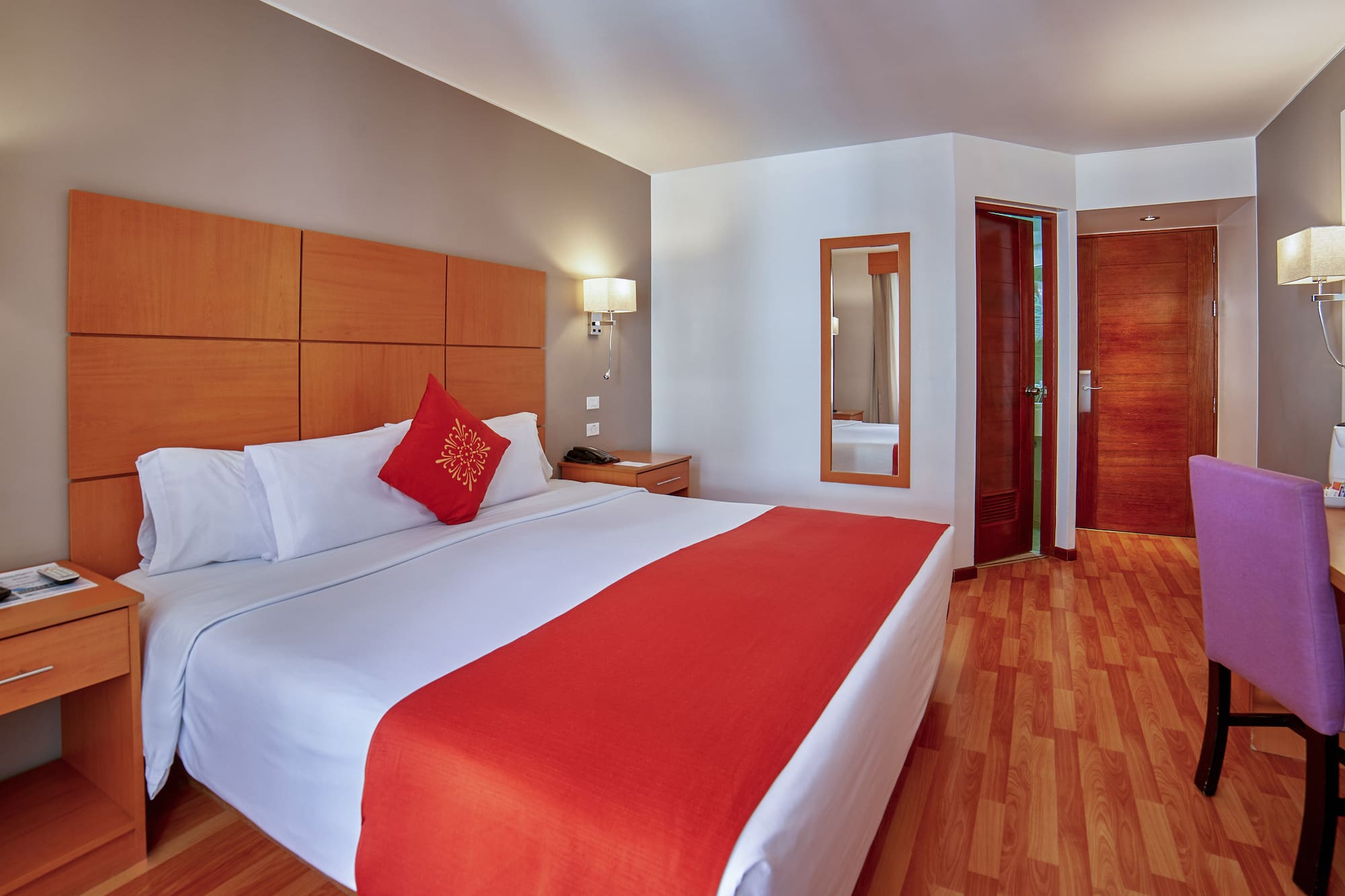 a bed with a red pillow and wood paneled headboard