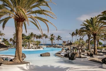 a pool with palm trees and umbrellas