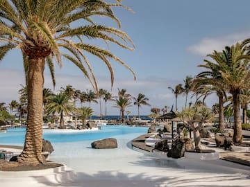 a pool with palm trees and umbrellas