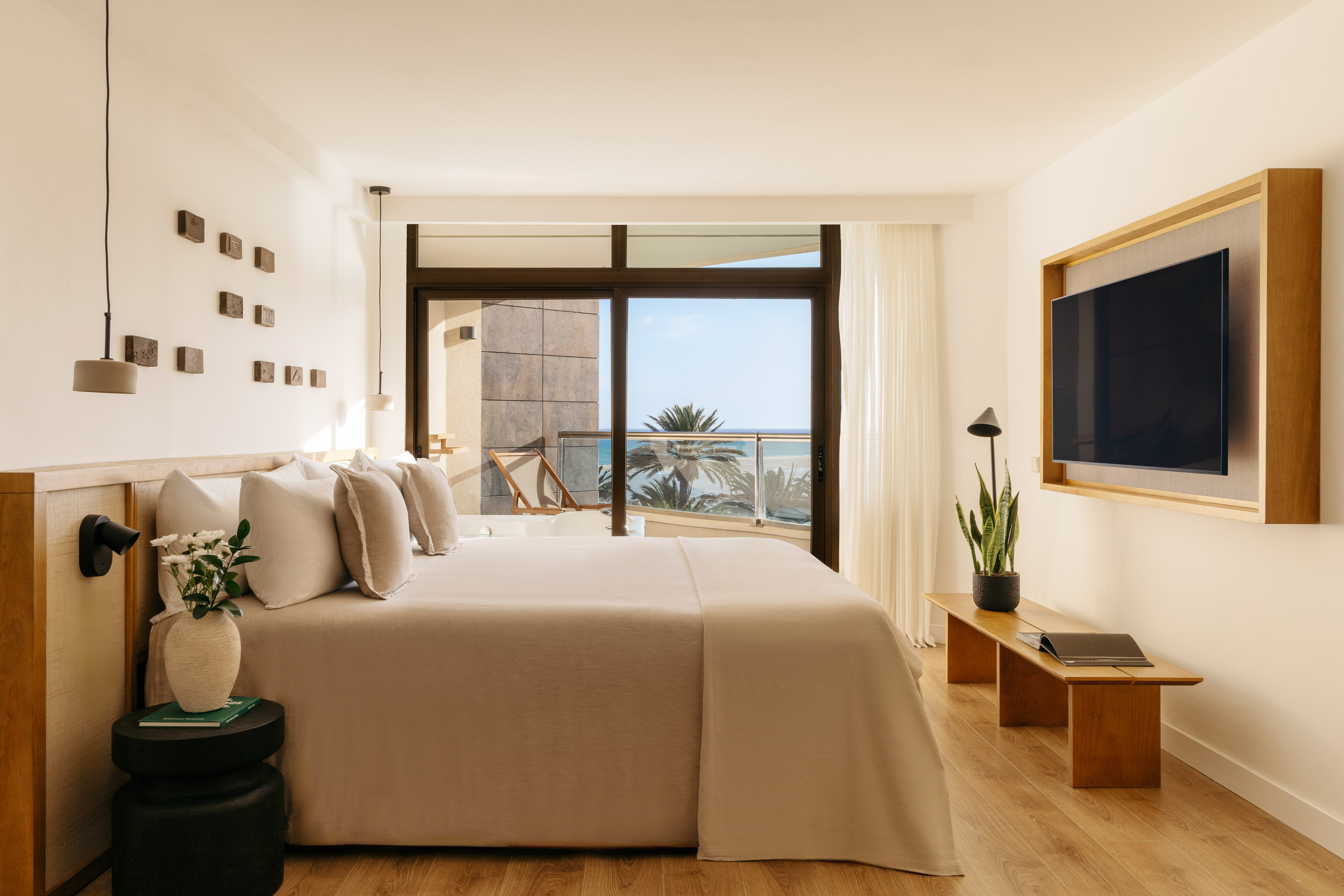 Modern hotel bedroom with ocean view balcony and king-sized bed.