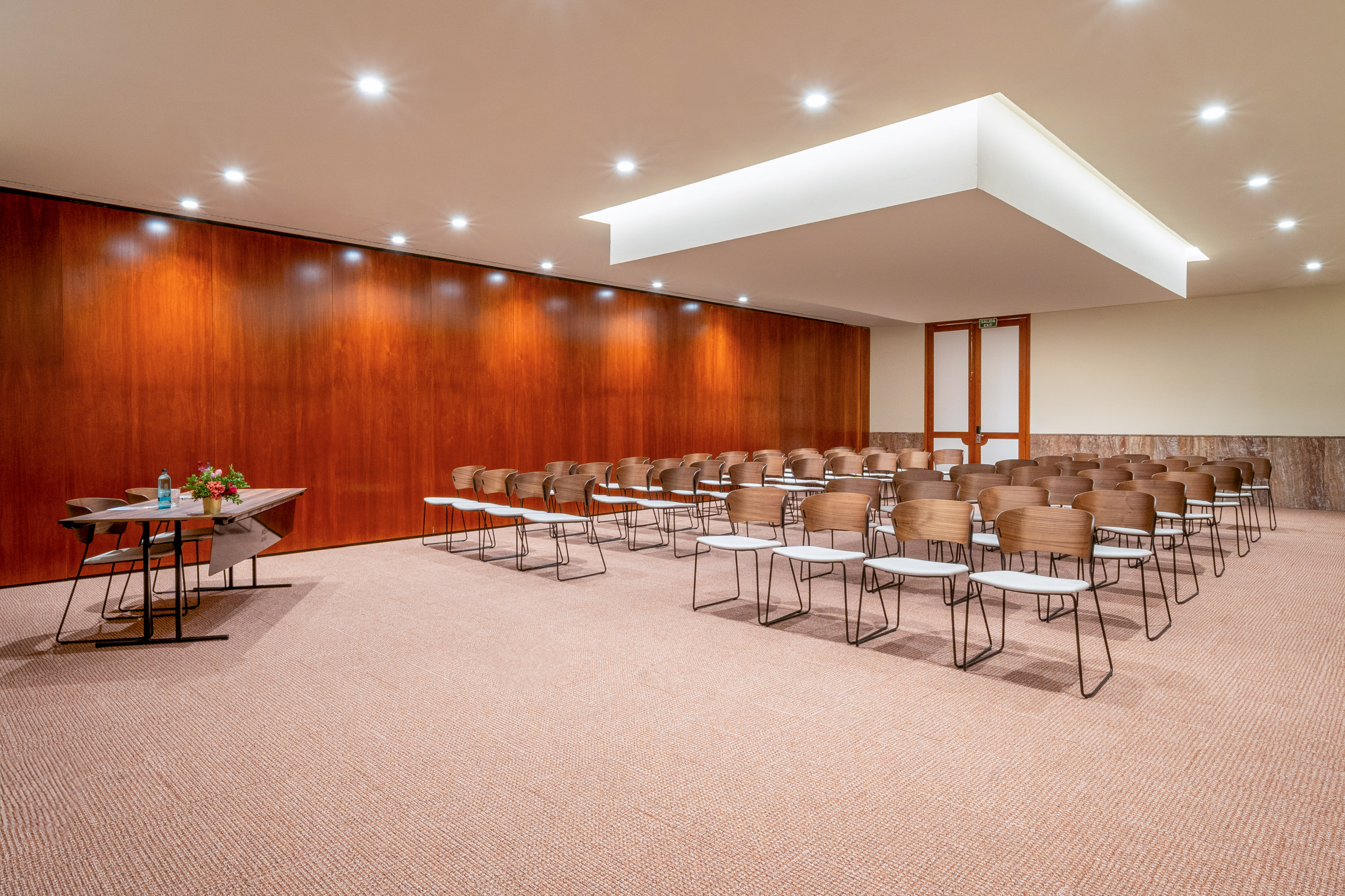 Modern meeting room with empty chairs, wood wall, and front table.