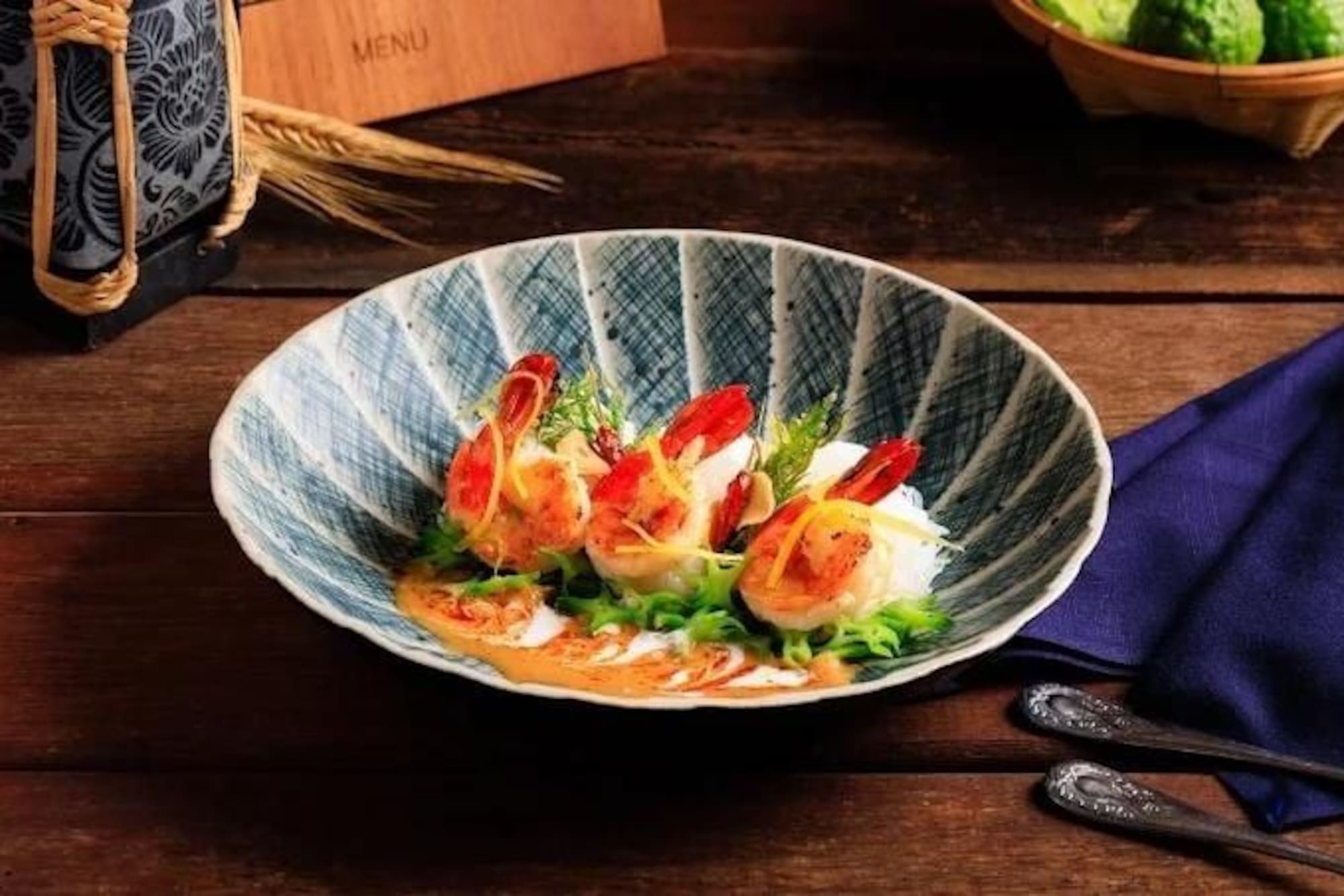 Seafood shrimp dish with sauce and fresh greens in a patterned bowl.