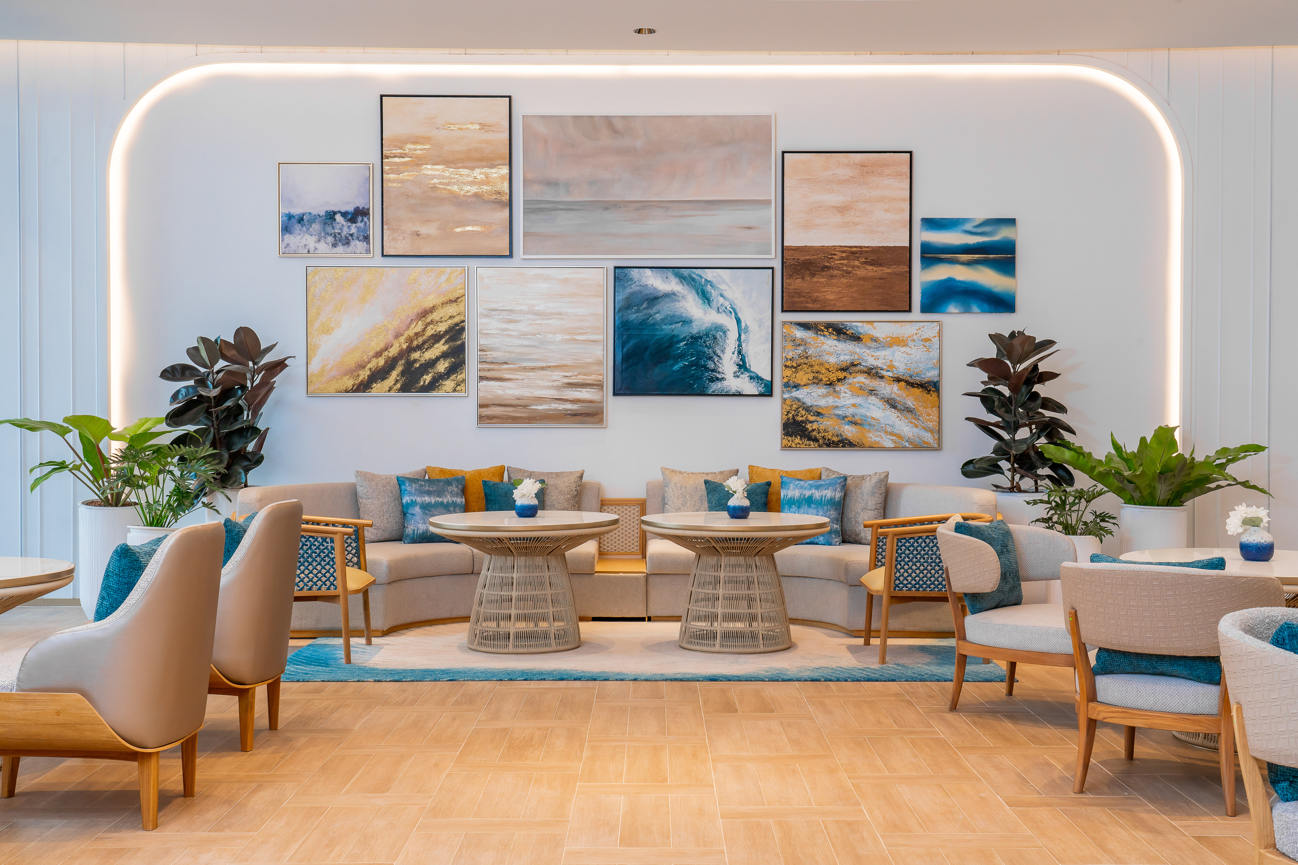 Modern lounge with abstract coastal art gallery, stylish seating, and green plants.
