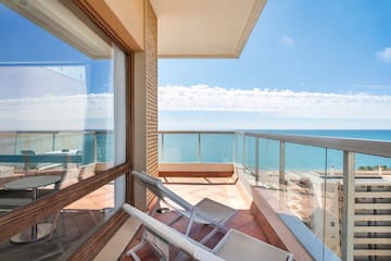 a deck with chairs and a glass railing overlooking the ocean