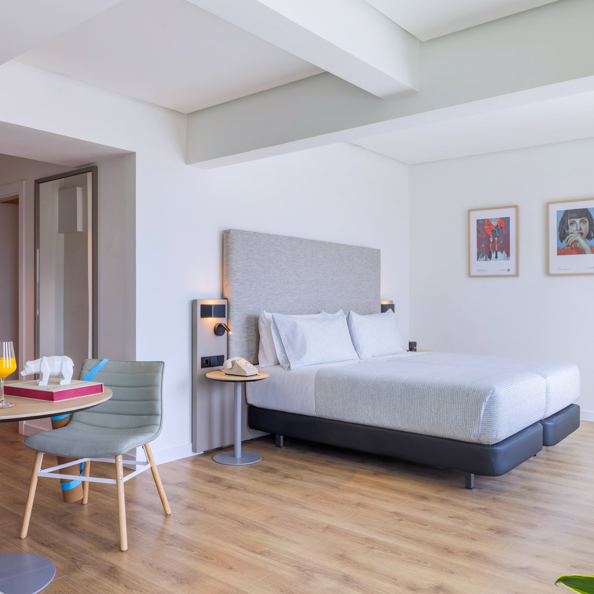 Suite de hotel moderna: cama, mesa con jugo, plantas, TV. Suelo de madera.