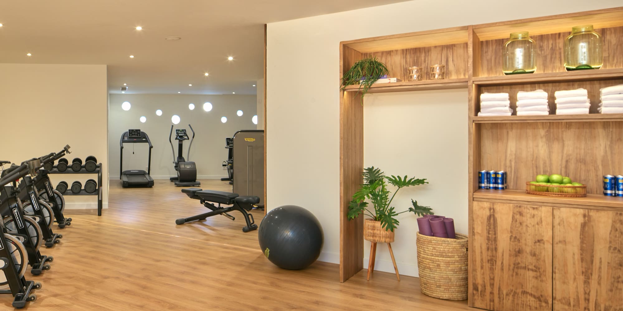 Modern gym with spin bikes, treadmill, weights, and refreshment station.