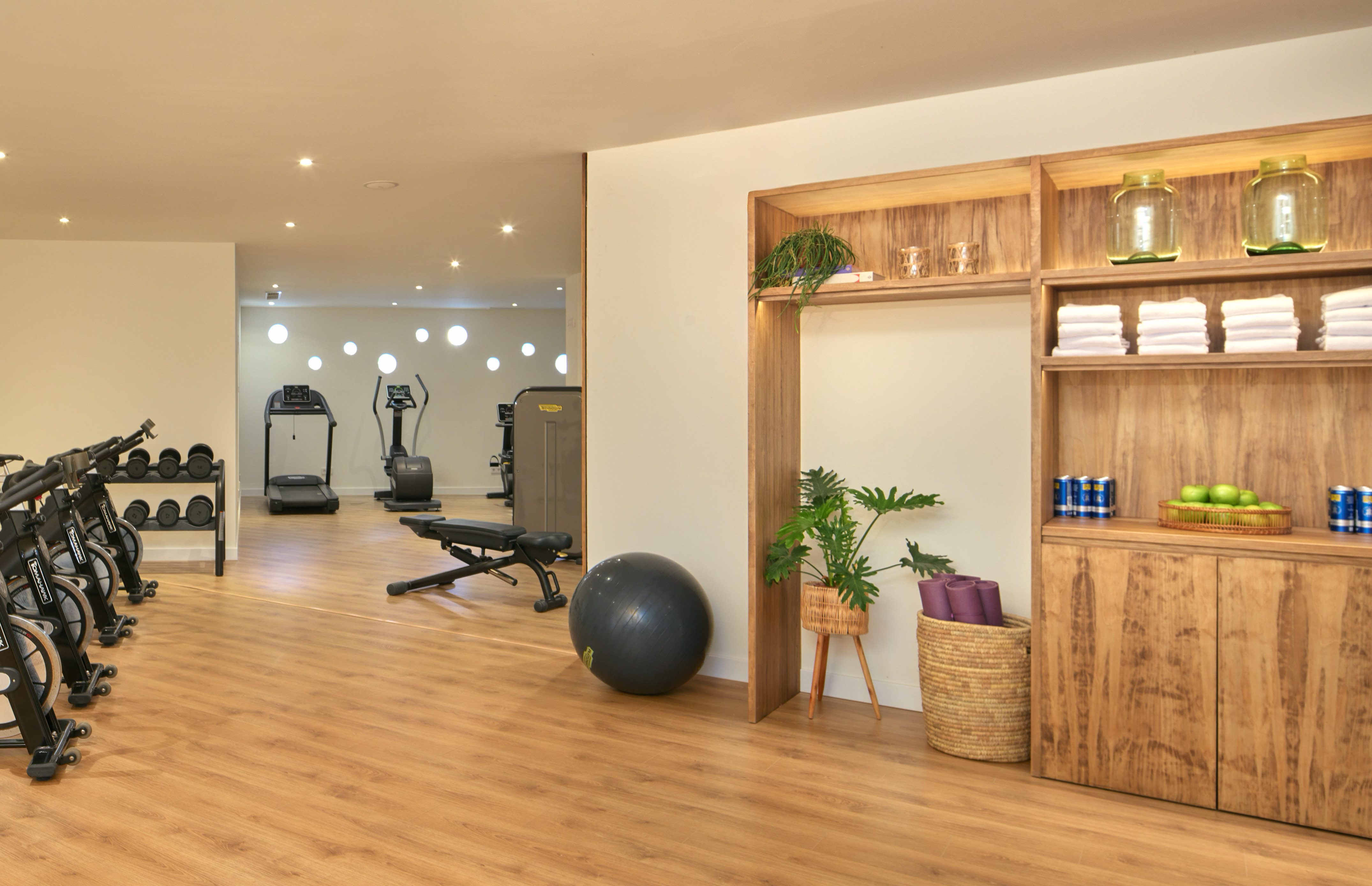 Modern gym with spin bikes, treadmill, weights, and refreshment station.