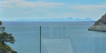 a table with wine glasses and food on it overlooking a body of water