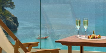 a table with wine glasses and food on it overlooking a body of water