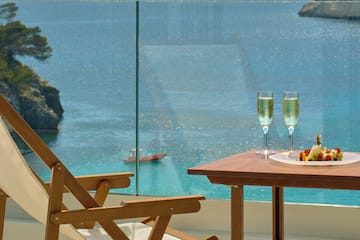 a table with wine glasses and food on it overlooking a body of water