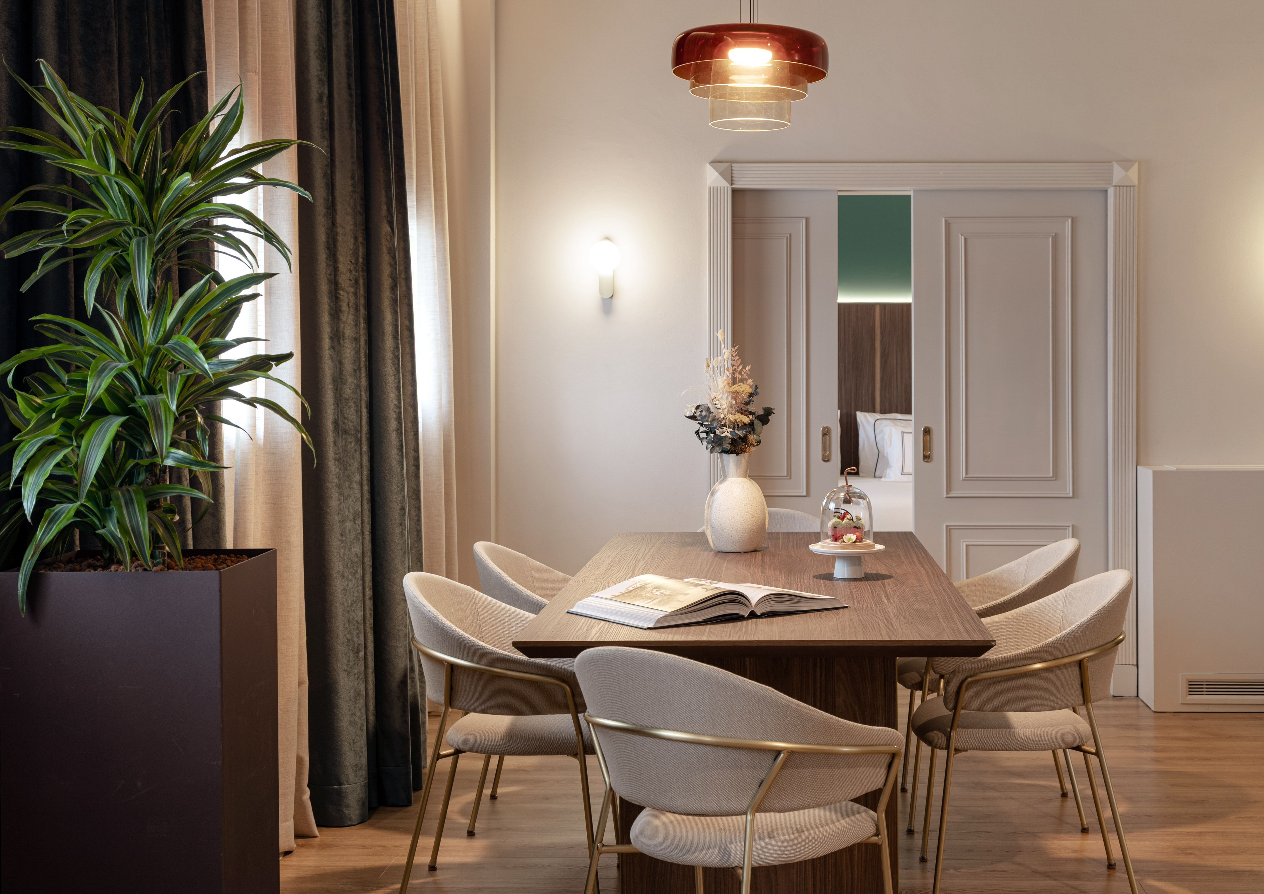 Elegant dining room with wooden table, gold-framed chairs, and modern decor.