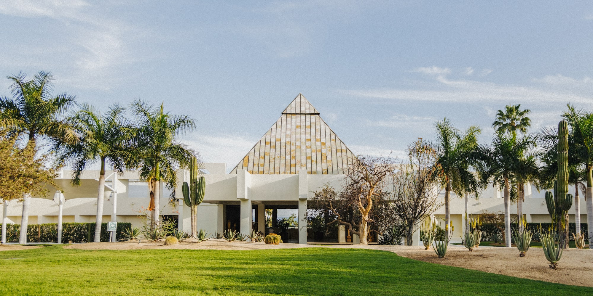 a building with a triangular roof and palm trees