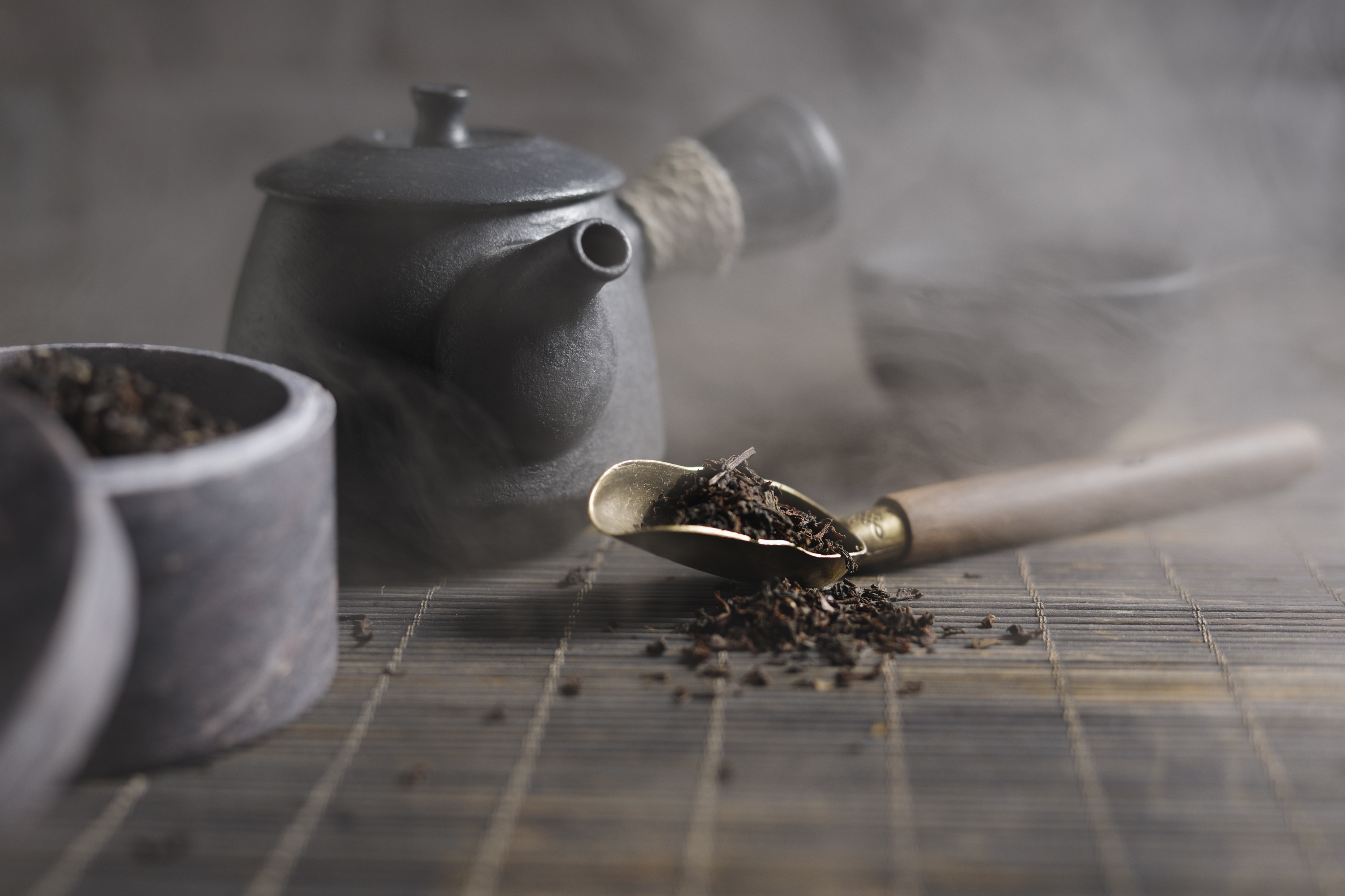 a teapot with a spoon full of tea leaves