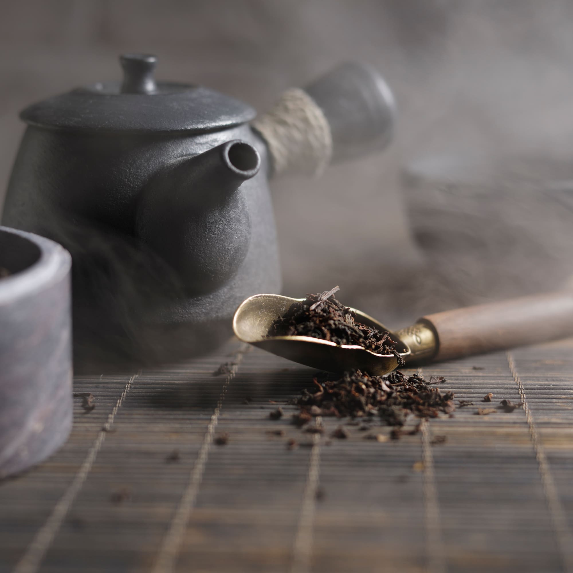 a teapot with a spoon full of tea leaves