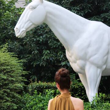 a woman looking at a statue of a horse