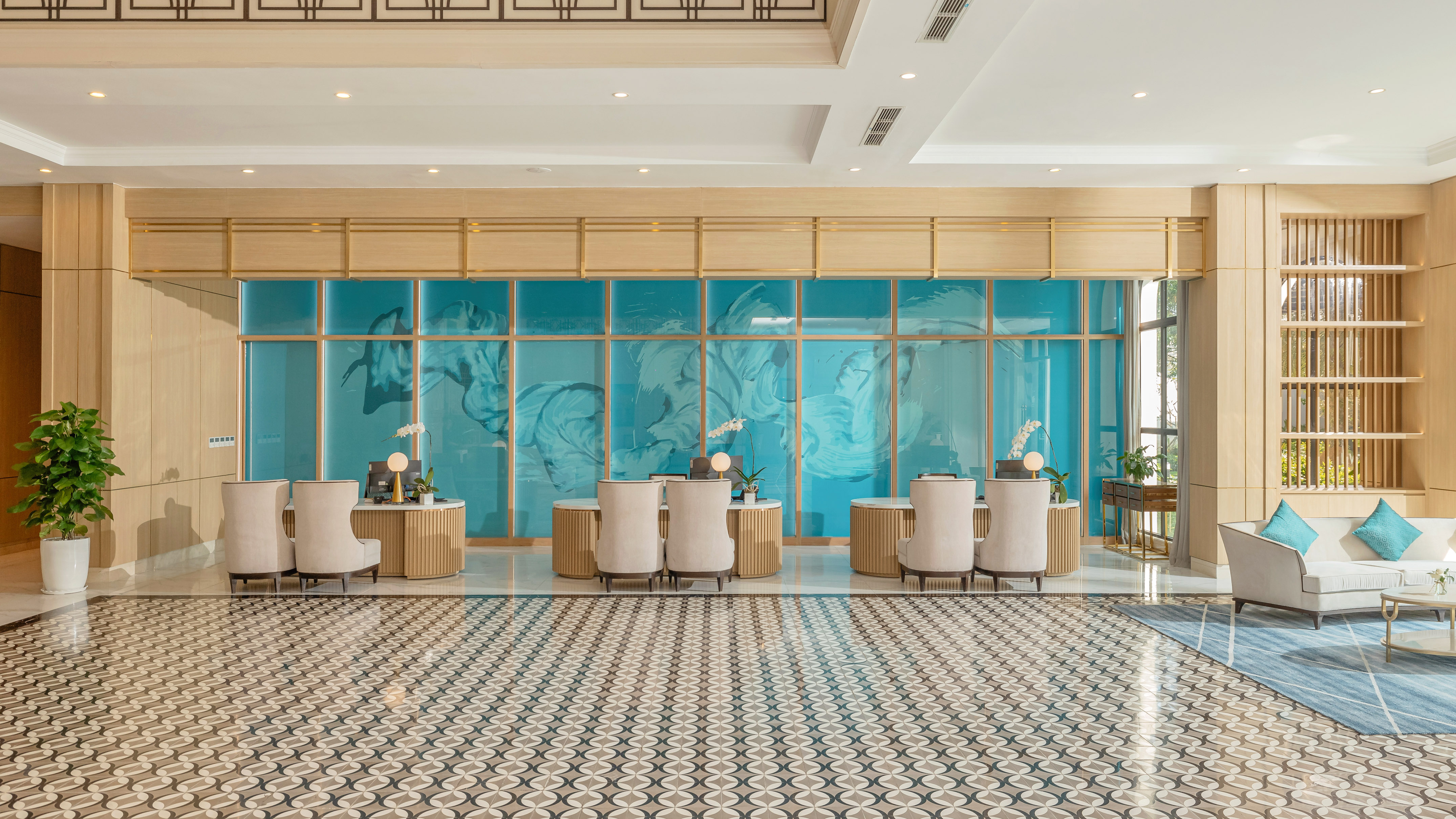 Modern hotel lobby, blue feature wall, three reception desks, patterned floor.
