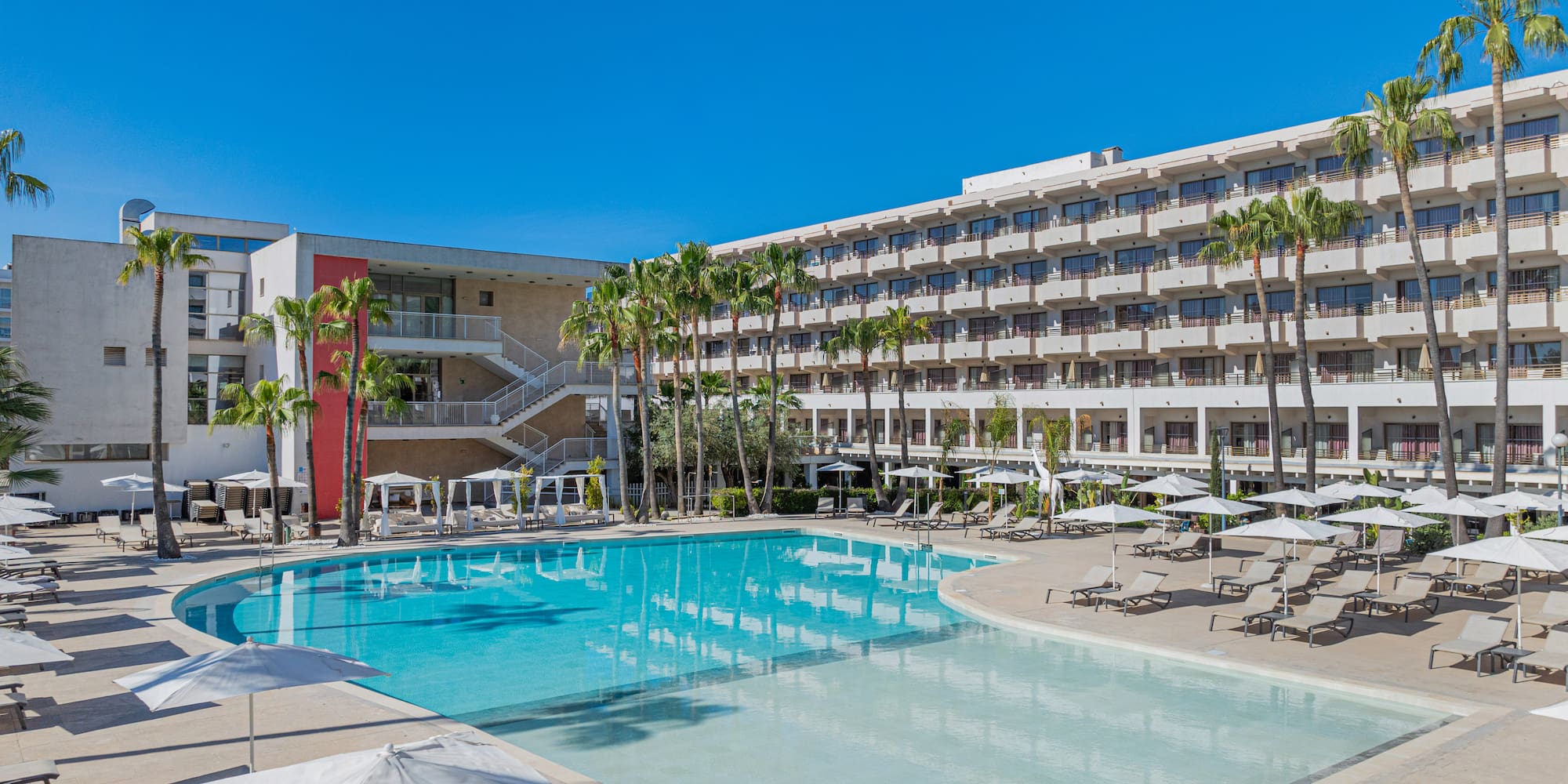 a pool with umbrellas and chairs in front of a building