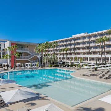 a pool with umbrellas and chairs in front of a building