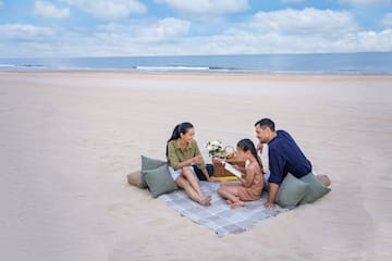 a group of people sitting on a blanket on a beach