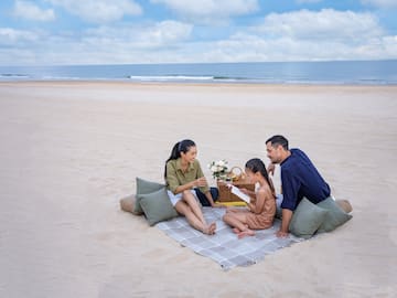 a group of people sitting on a blanket on a beach