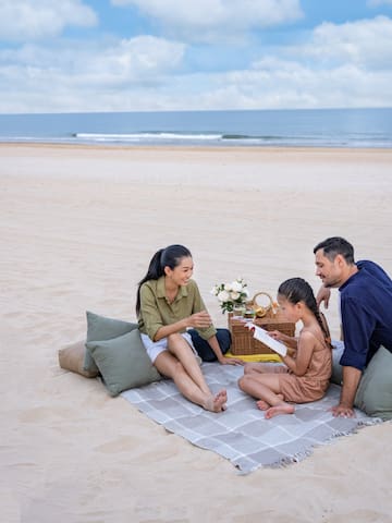 a group of people sitting on a blanket on a beach