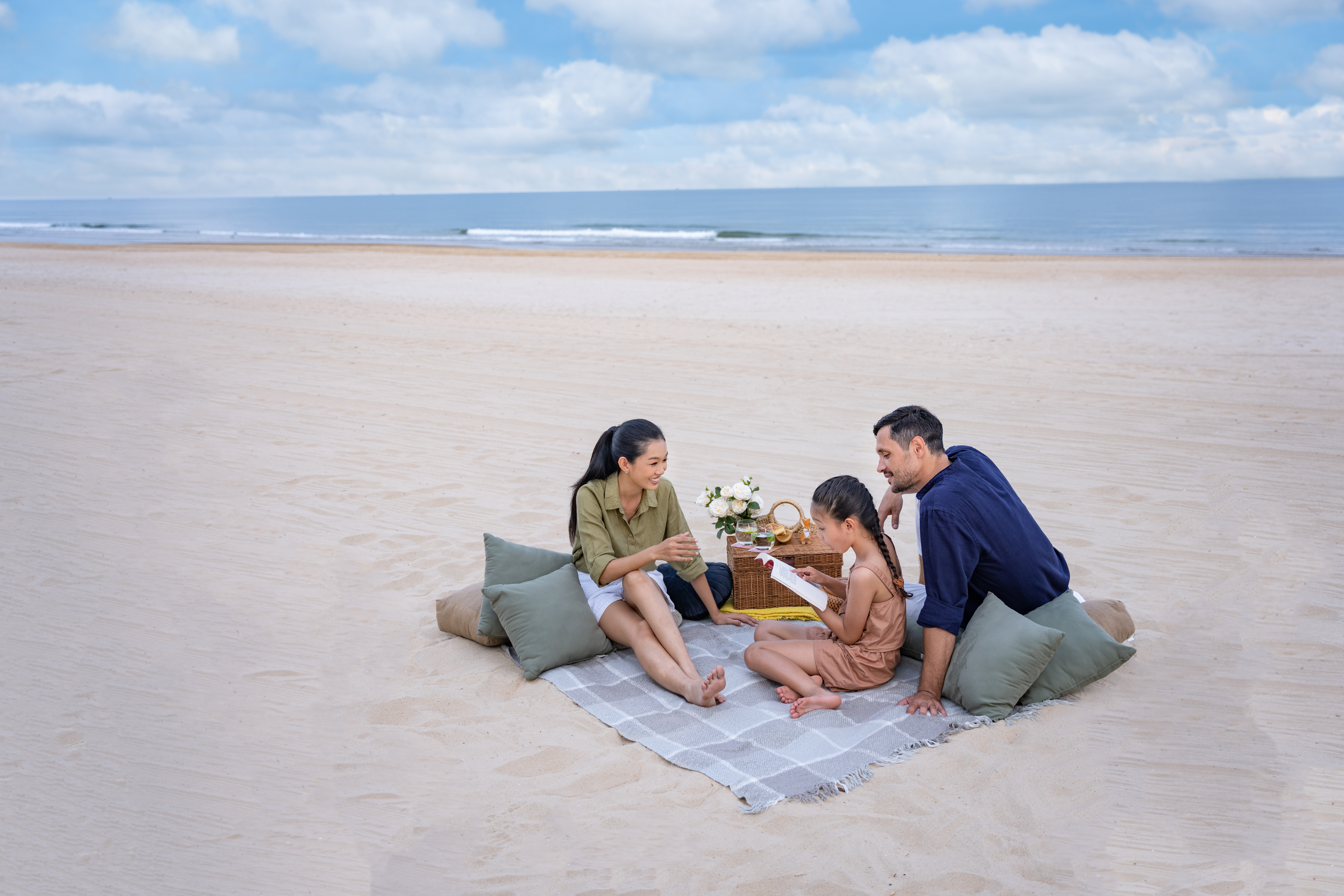 a group of people sitting on a blanket on a beach