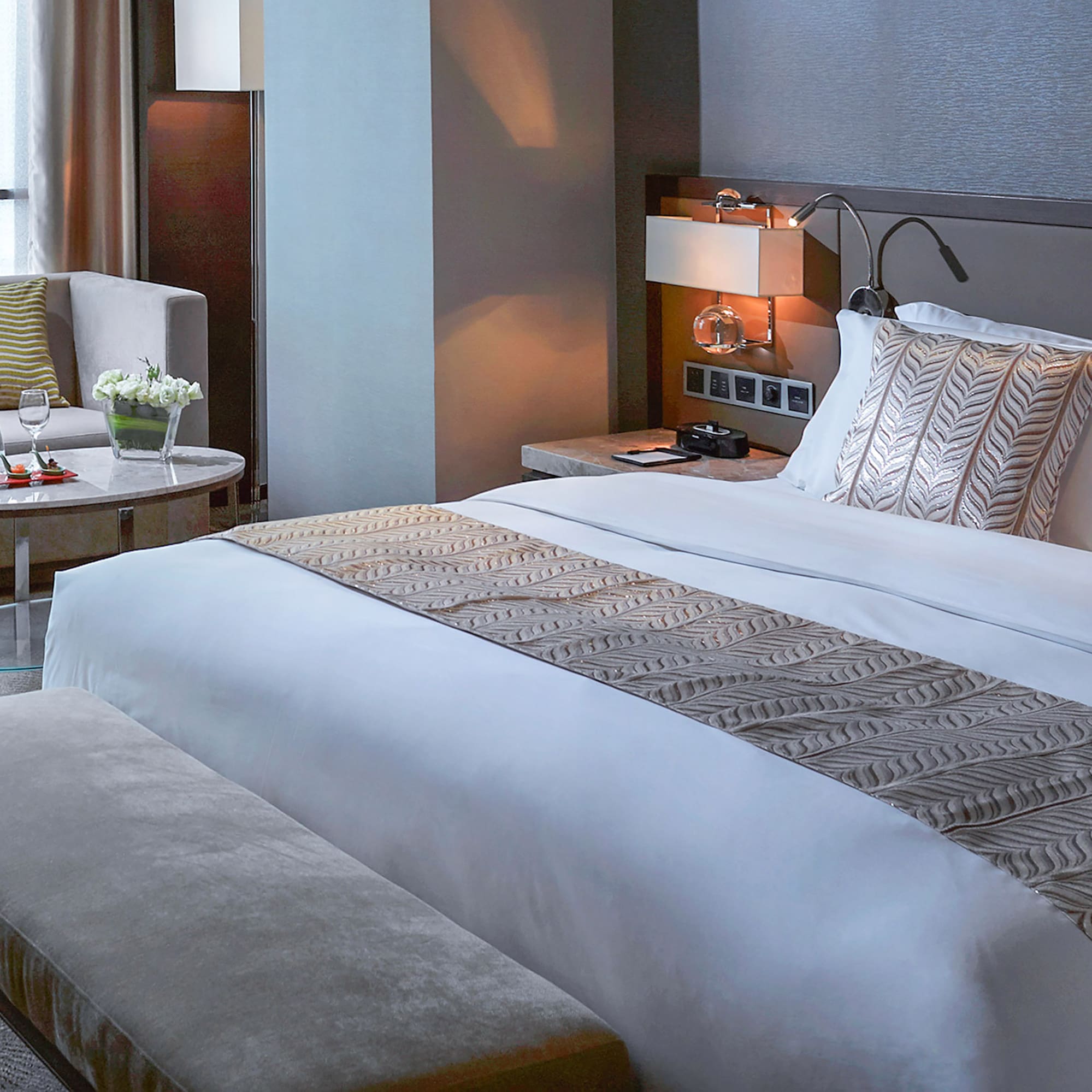 a bed with a bench and a chair in a hotel room