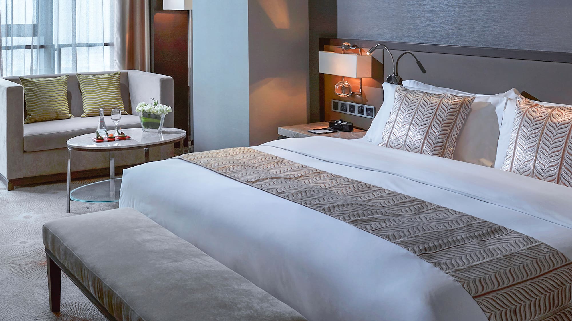 a bed with a bench and a chair in a hotel room