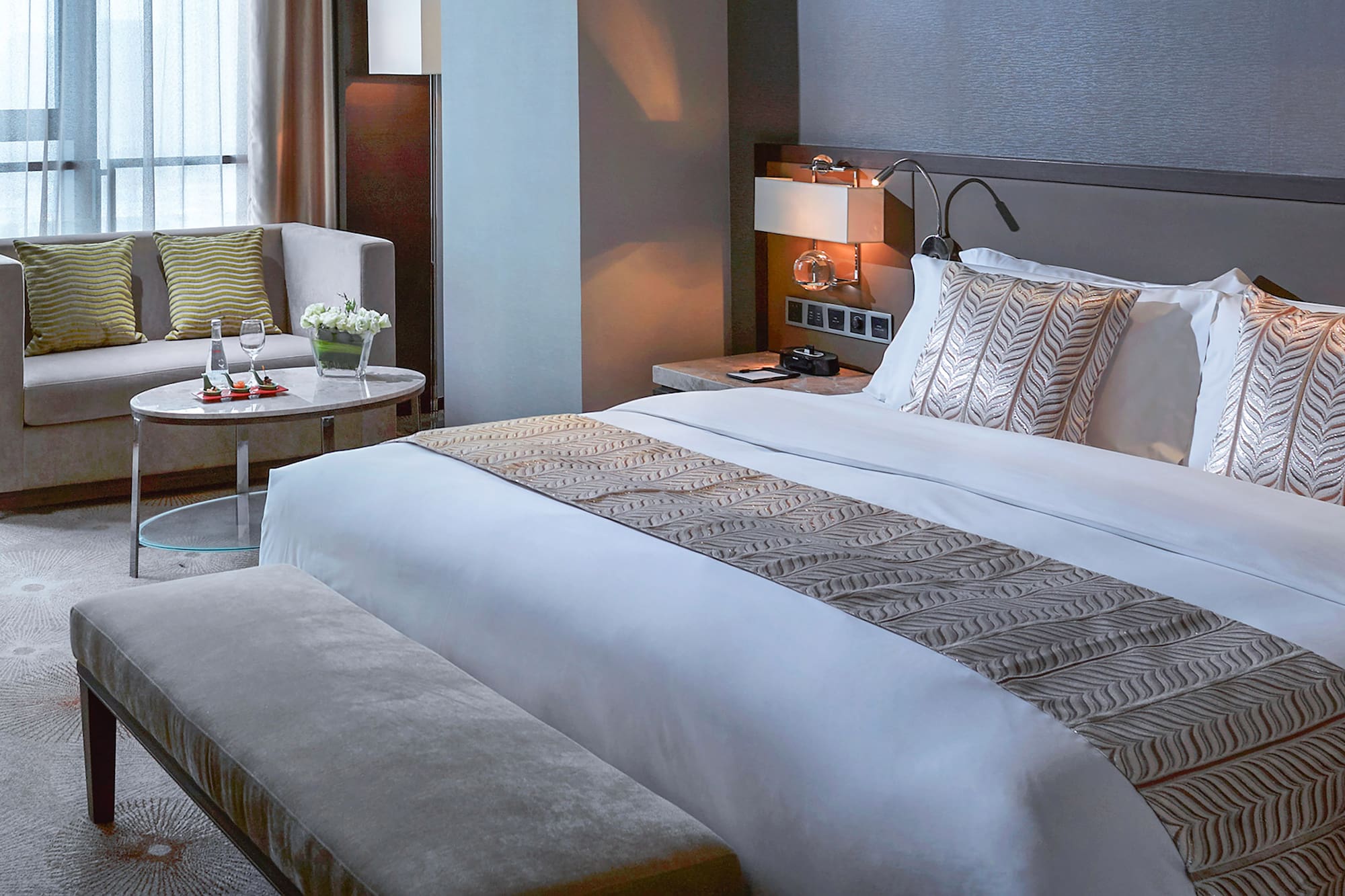 a bed with a bench and a chair in a hotel room