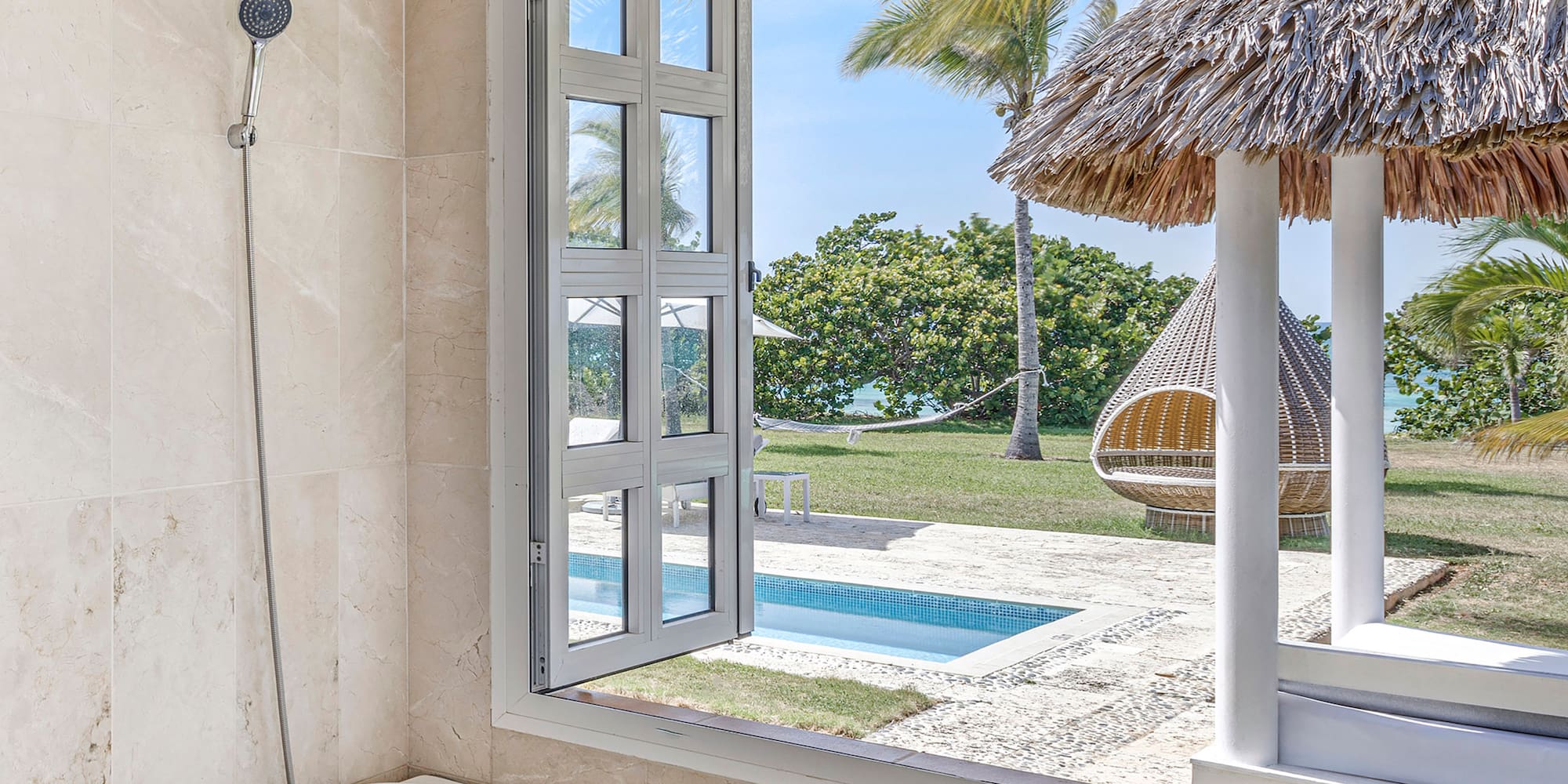 a bathtub with a straw hut and a pool outside