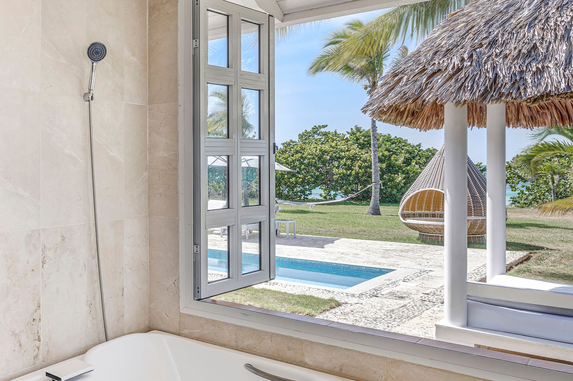 a bathtub with a straw hut and a pool outside
