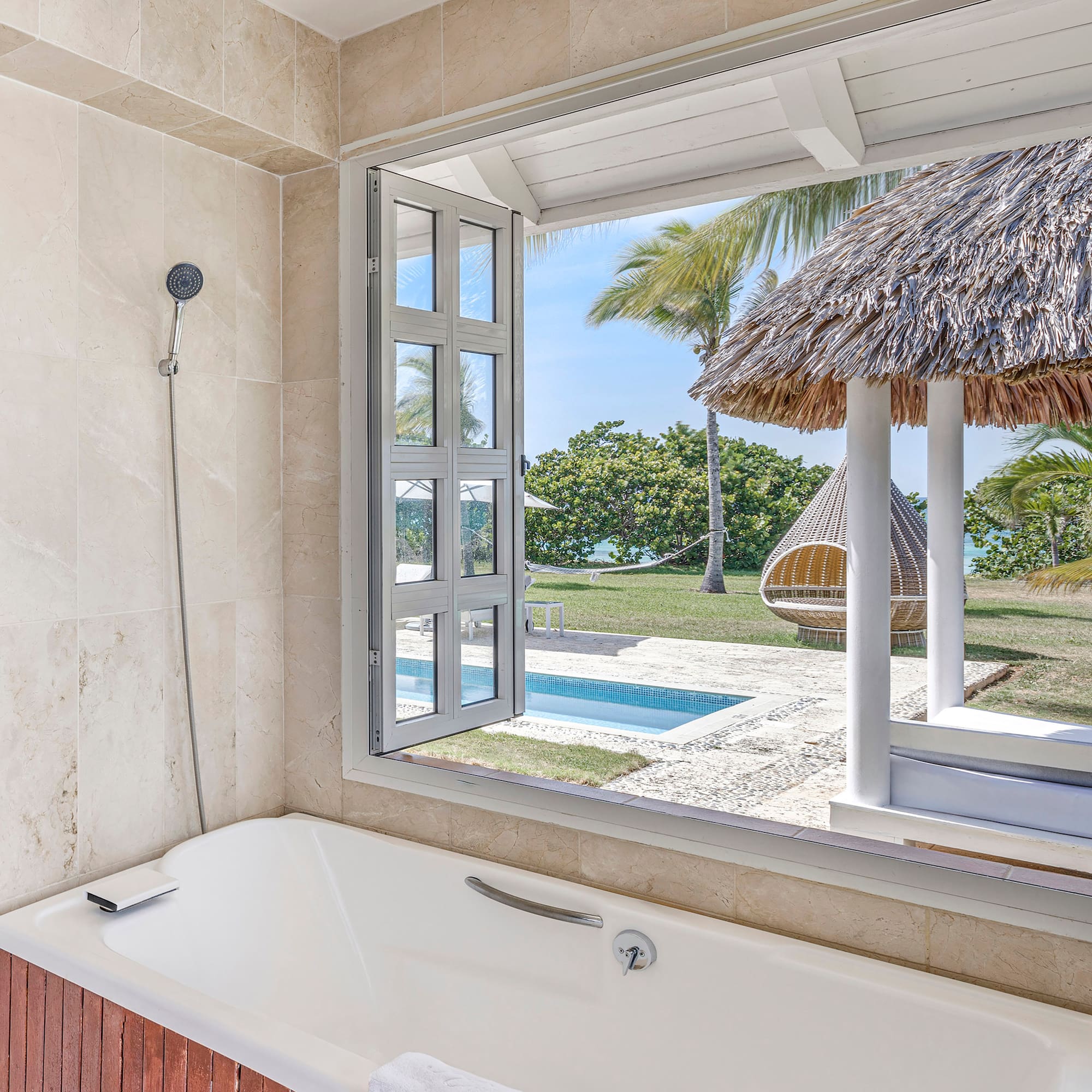 a bathtub with a straw hut and a pool outside