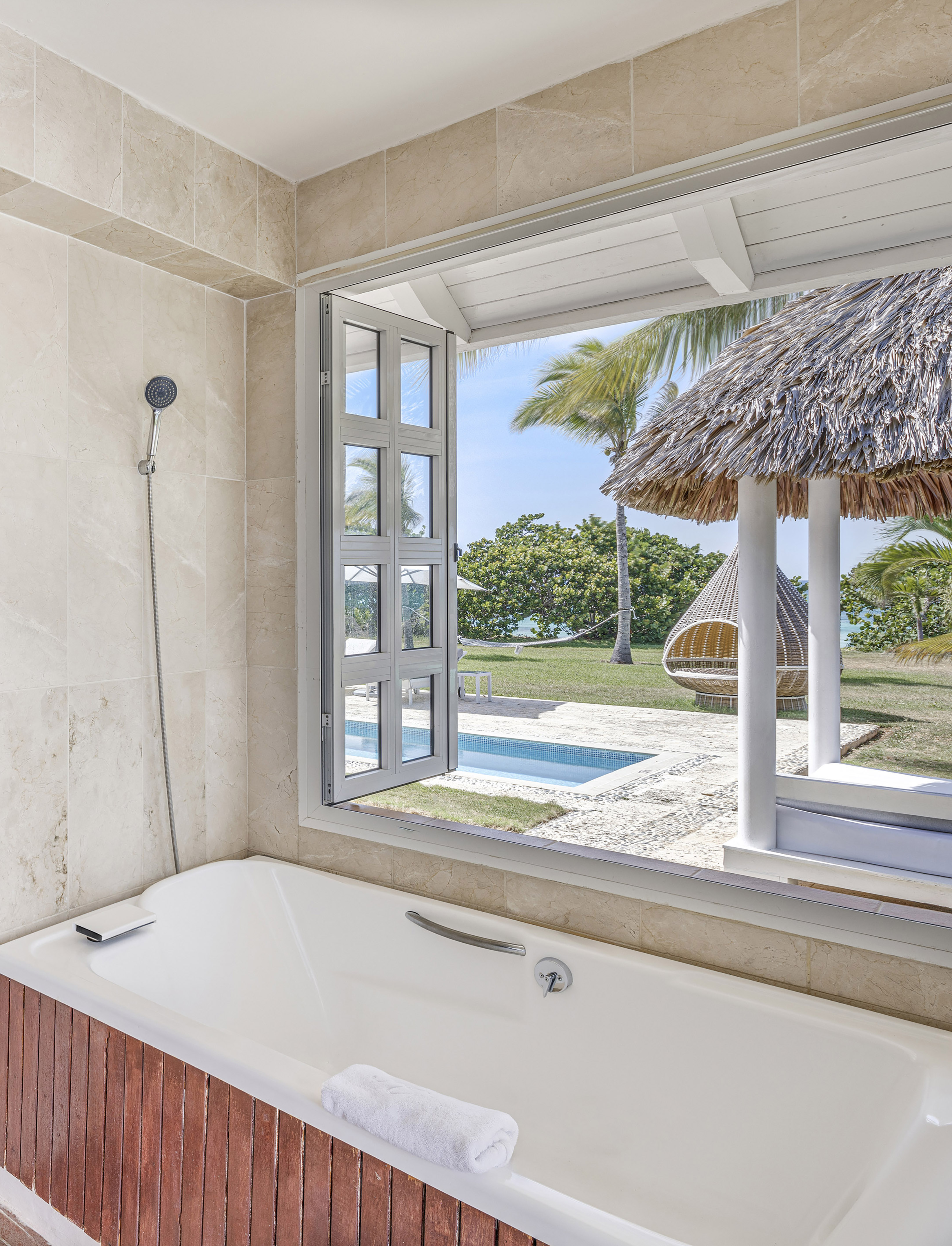 a bathtub with a straw hut and a pool outside