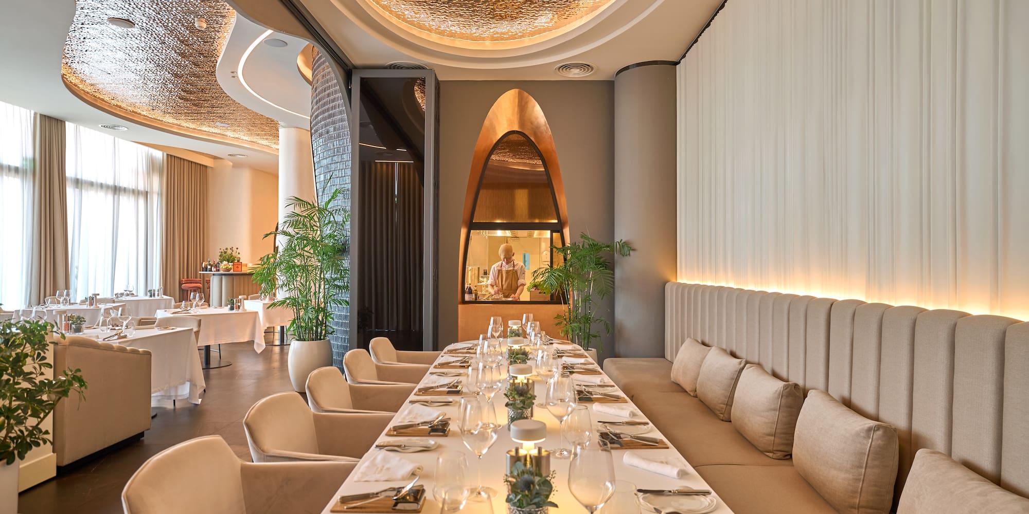 a long table with white chairs and plates on it