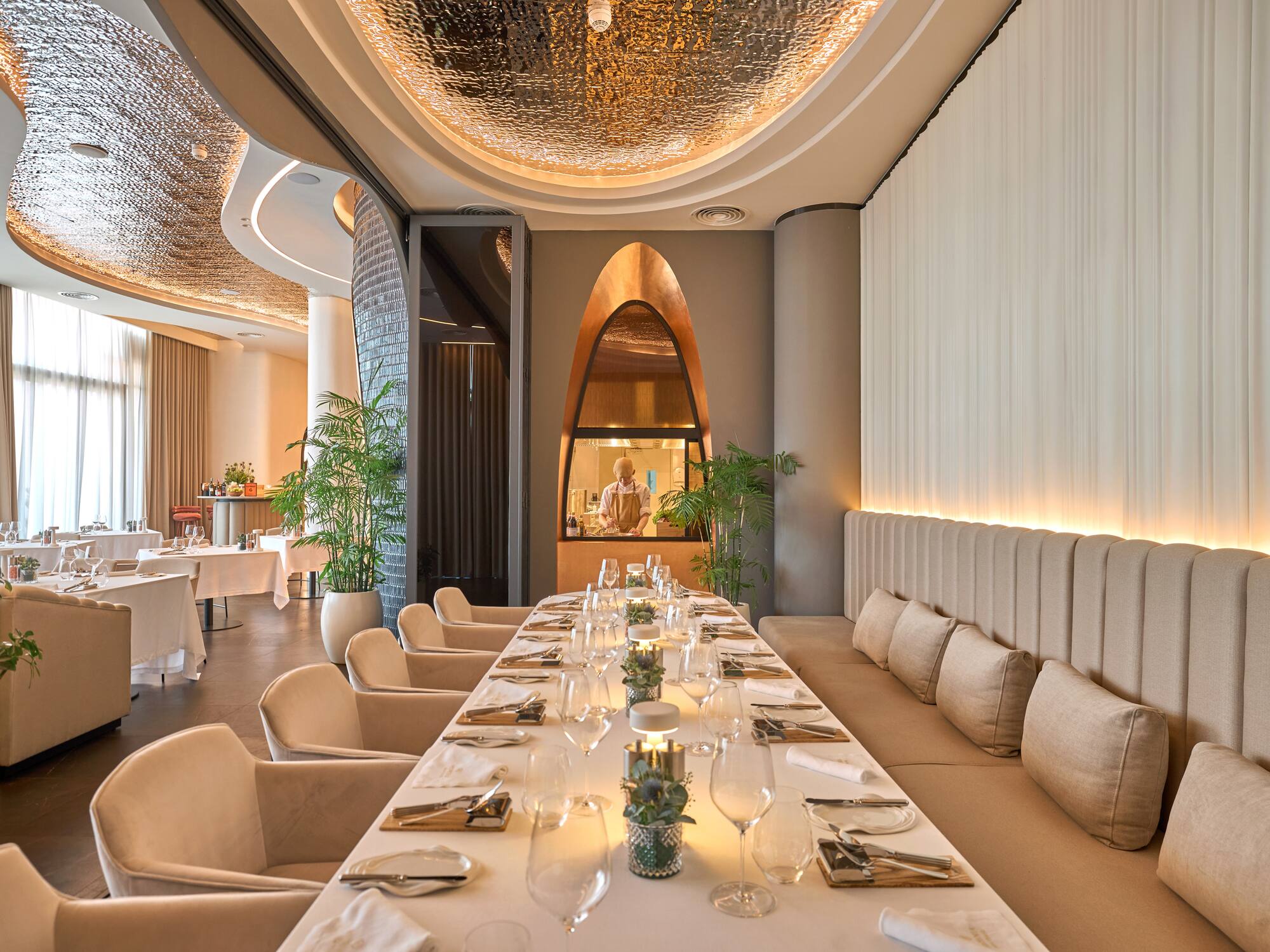 a long table with white chairs and plates on it