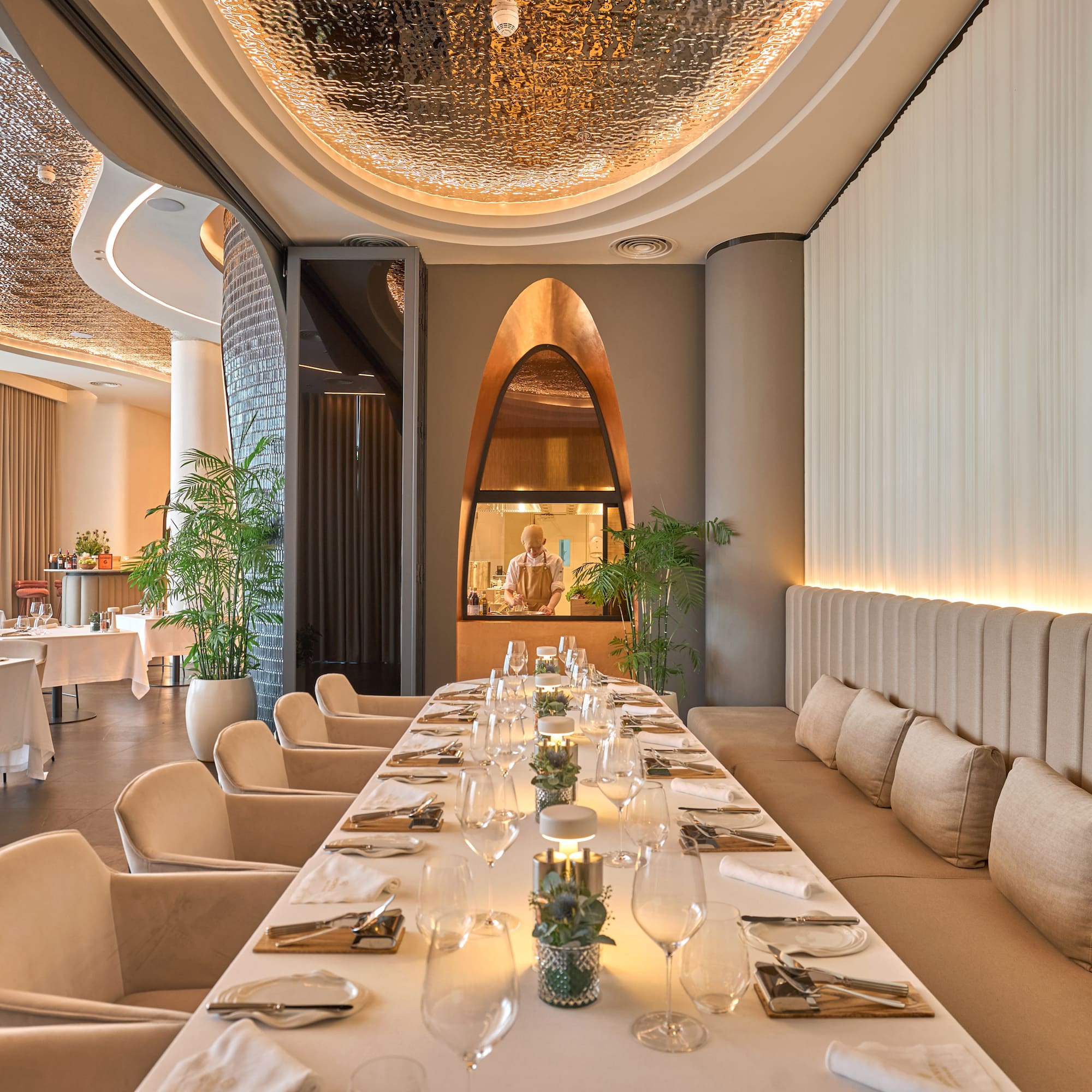 a long table with white chairs and plates on it