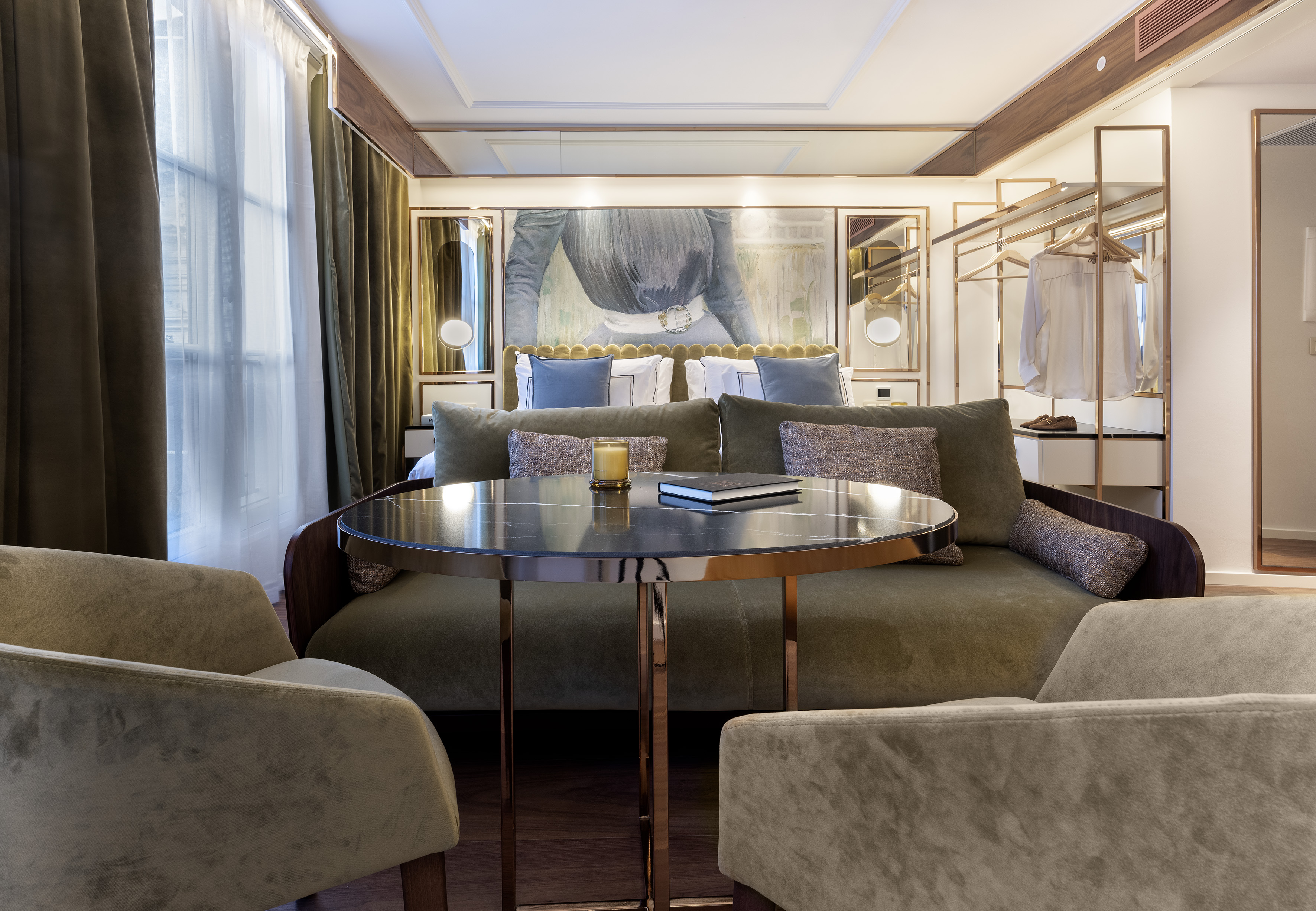 Boutique hotel suite with green velvet sofa, marble table, and modern decor.