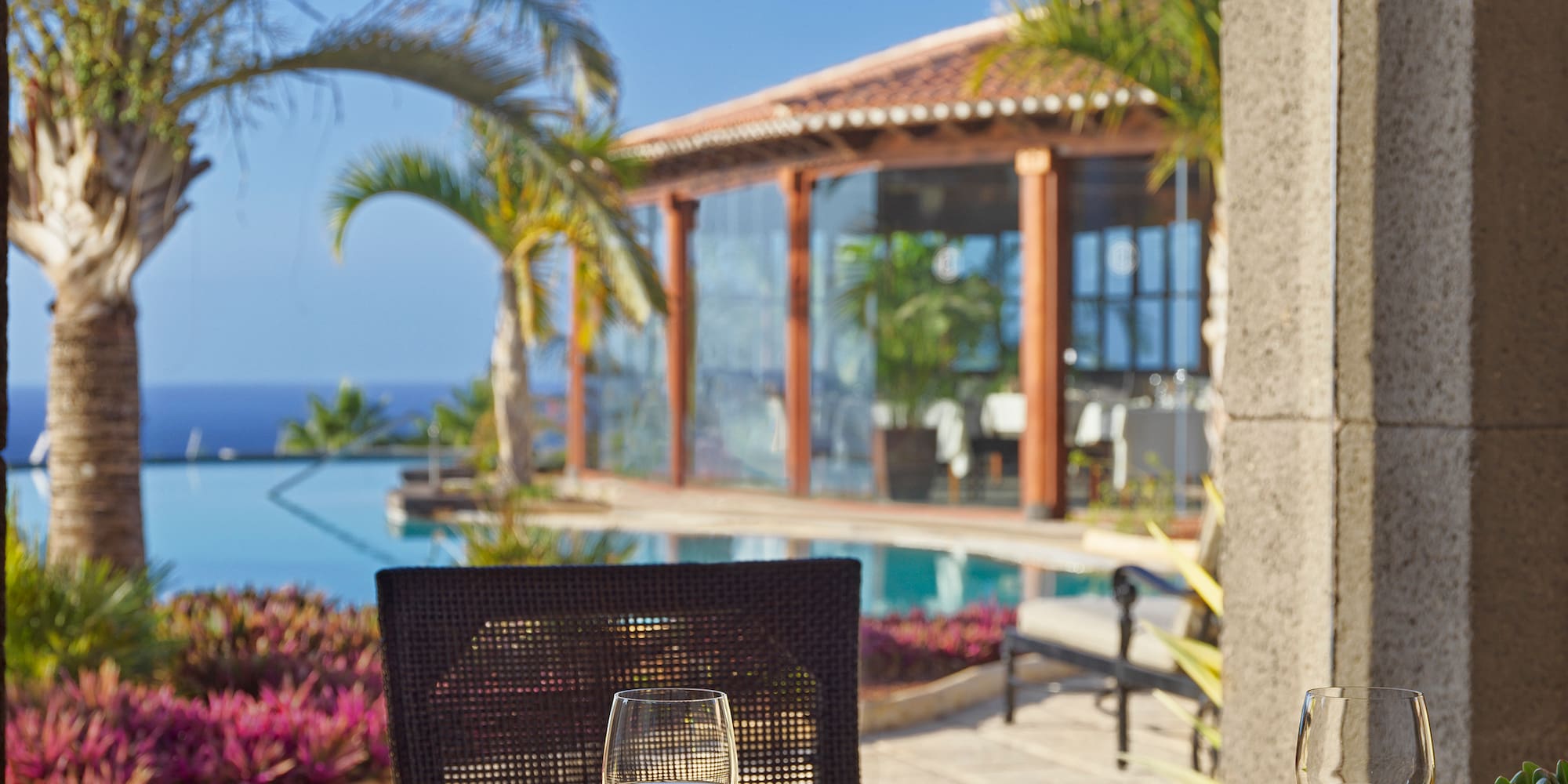 Outdoor dining table with wine at a luxury resort, ocean view and pool.
