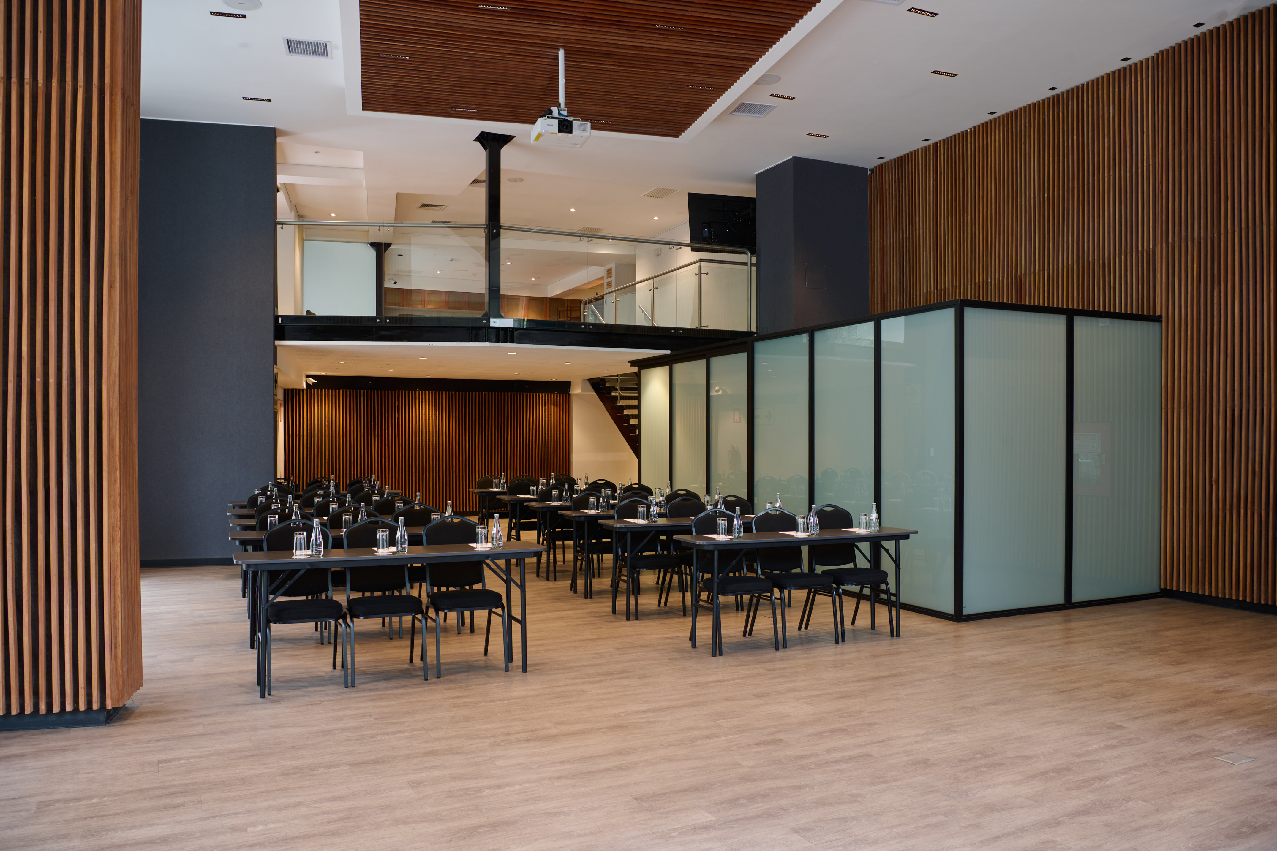 Modern conference room with classroom setup, wood walls, and projector.