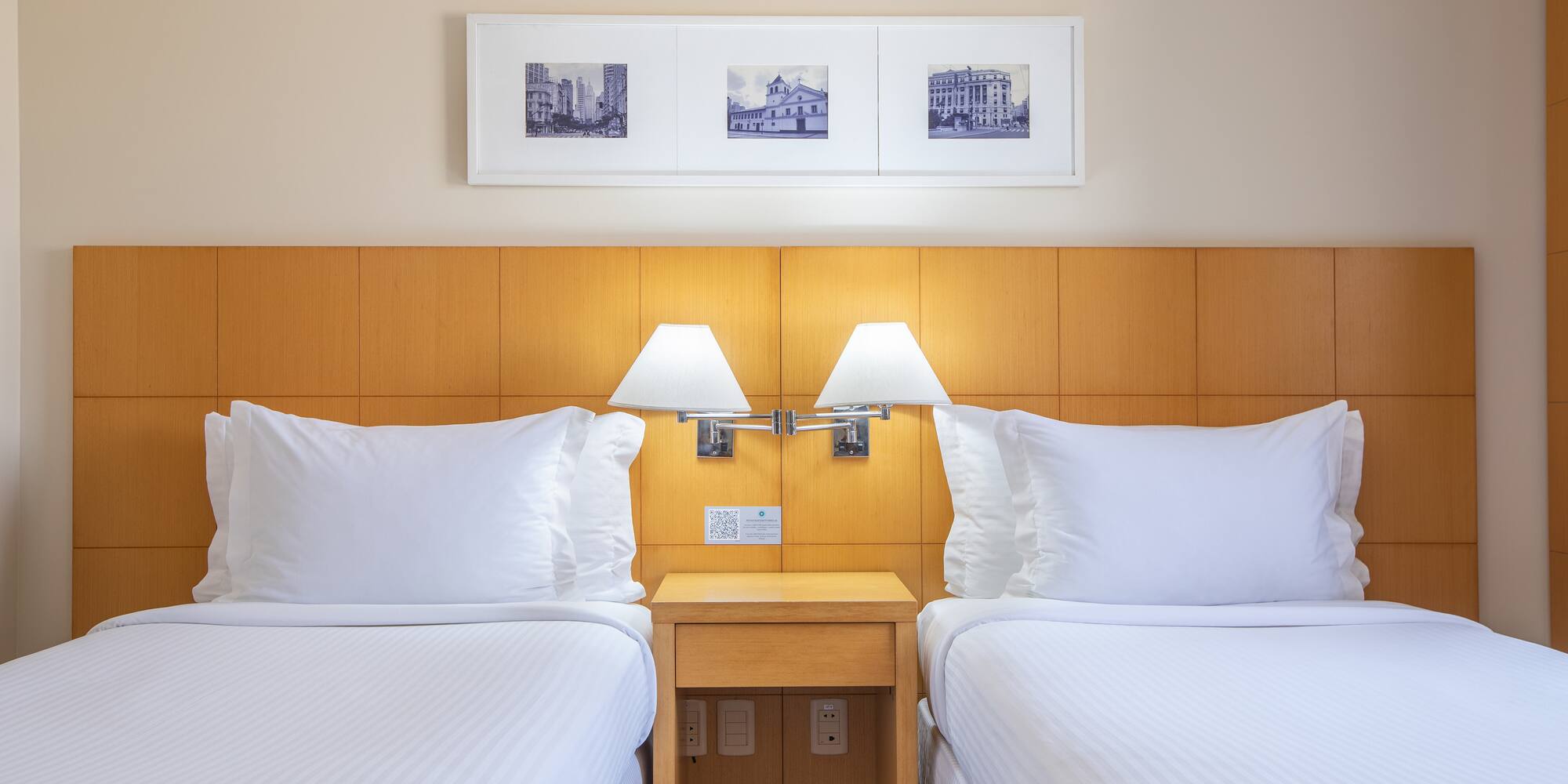 two beds with white sheets and lamps in a hotel room